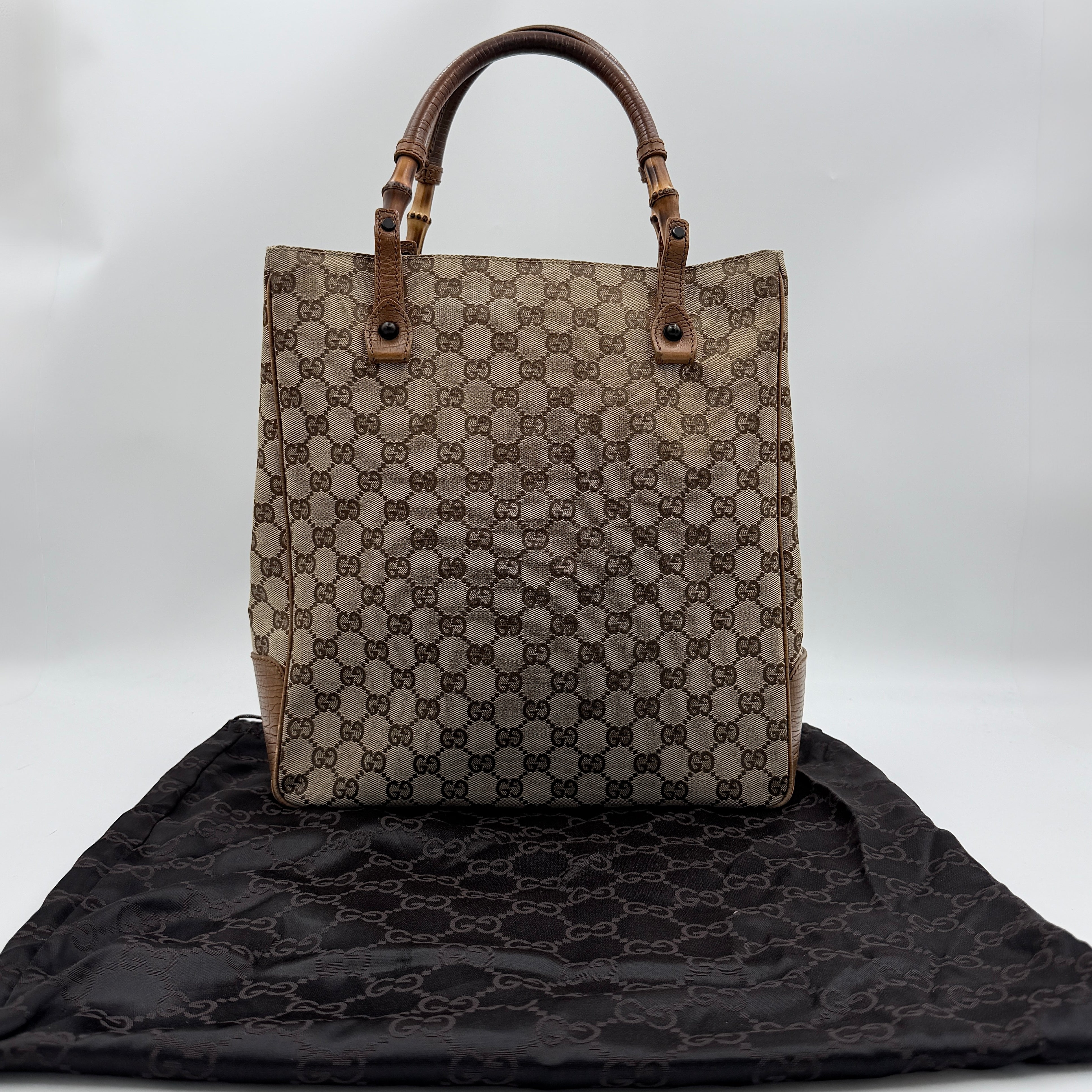 Gucci GG Monogram Bamboo Shoulder Bag in beige and brown canvas with bamboo top handles displayed upright.