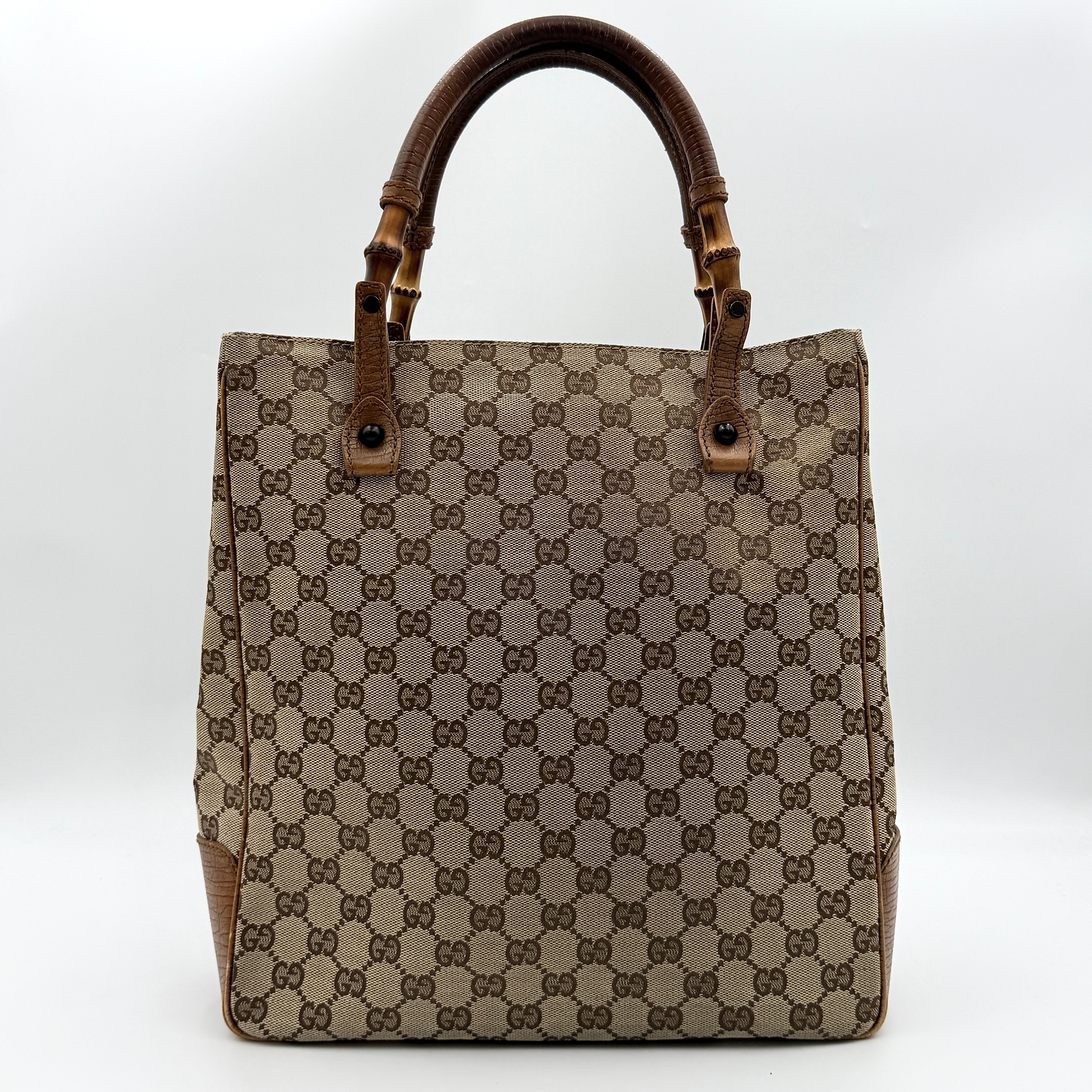 Gucci GG Monogram Bamboo Shoulder Bag in beige and brown canvas with bamboo top handles displayed upright.