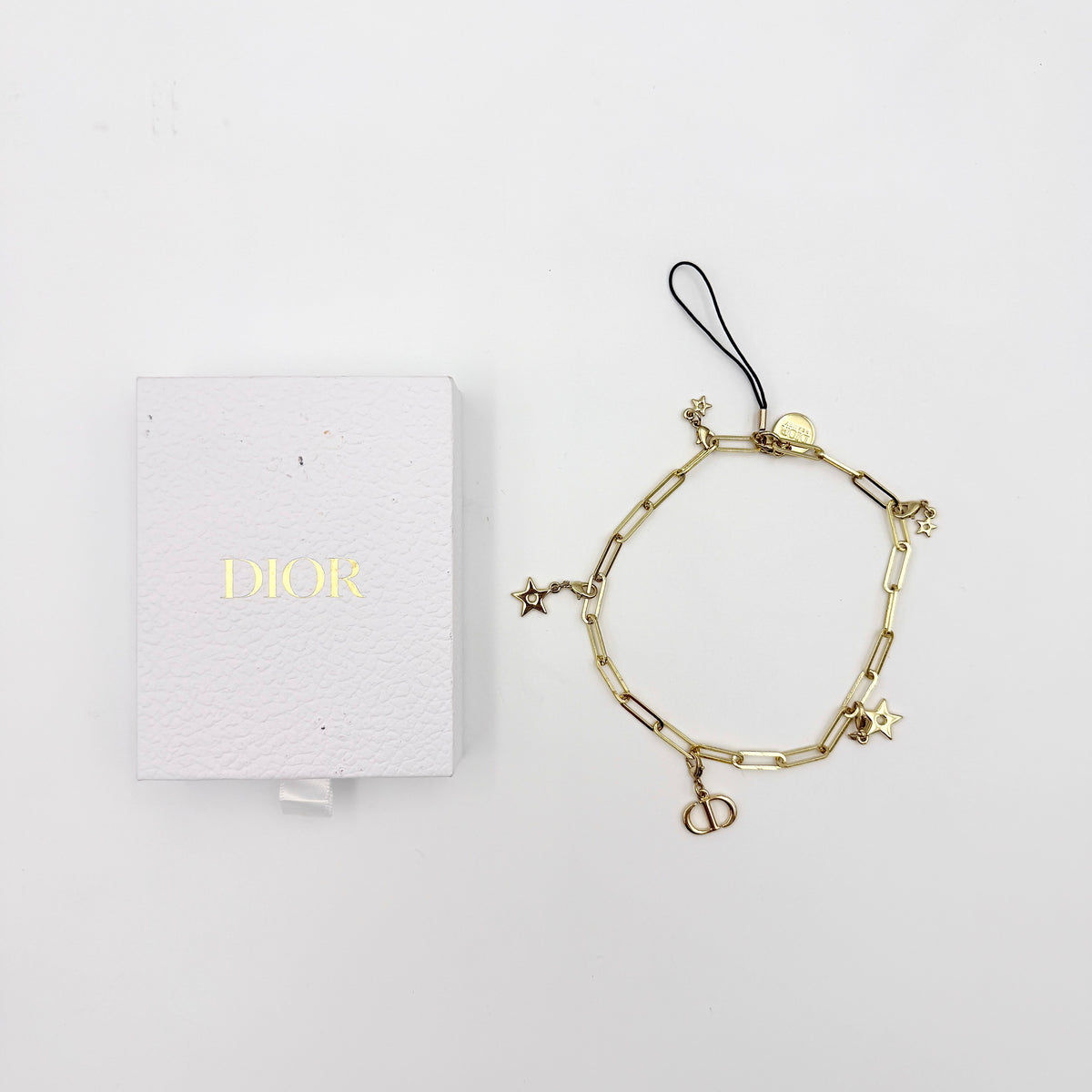 Christian Dior gold-tone phone strap with CD logo and star charms, styled with original Dior box.