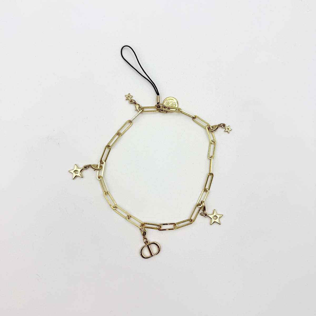 Christian Dior gold-tone phone strap with CD logo and star charms, styled with original Dior box.