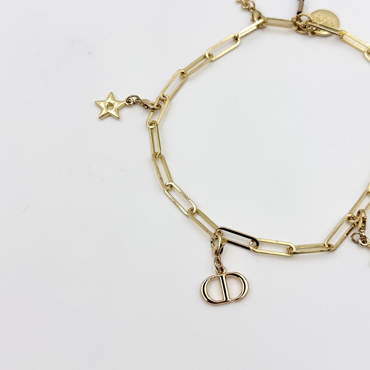 Christian Dior gold-tone phone strap with CD logo and star charms, styled with original Dior box.