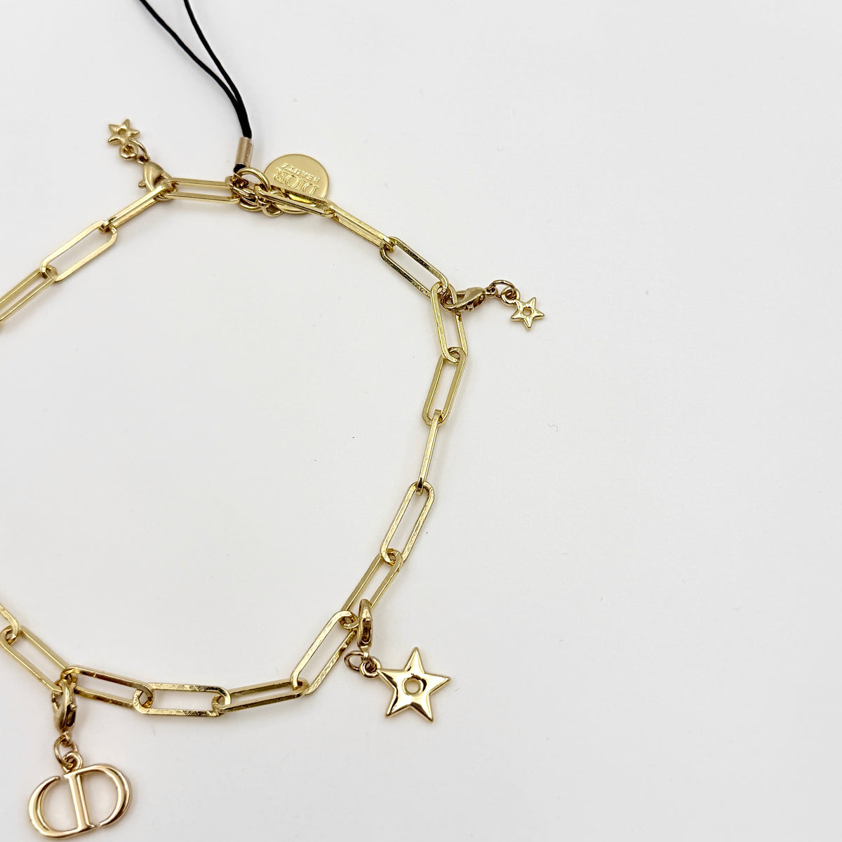 Christian Dior gold-tone phone strap with CD logo and star charms, styled with original Dior box.