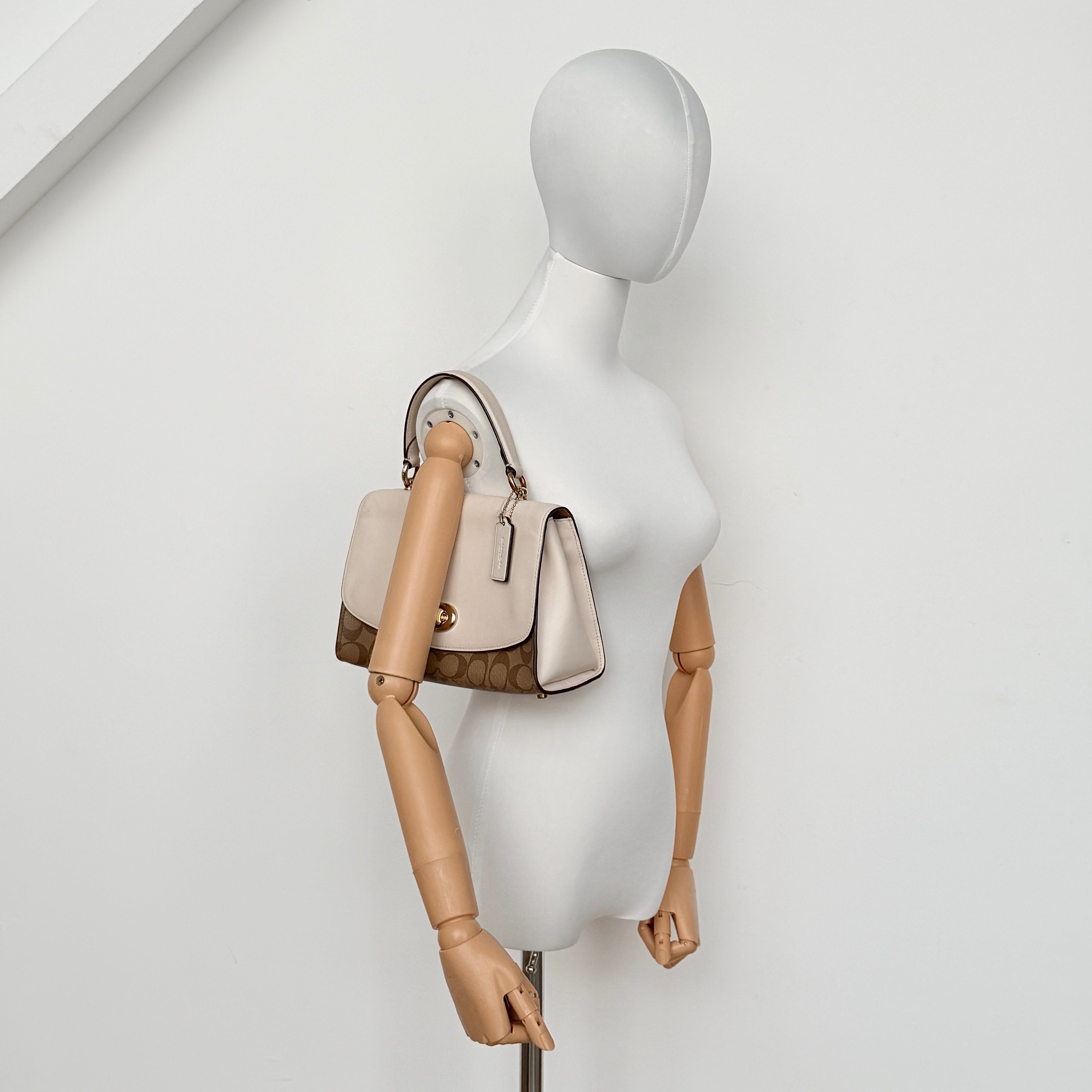 Coach Signature Tilly Top Handle Bag in beige and white with gold-tone hardware and detachable strap, displayed against a clean background.