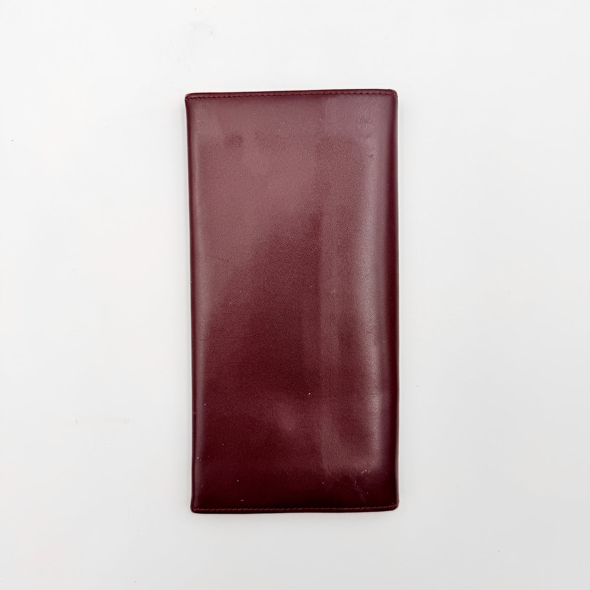 Cartier Must de Cartier bifold long wallet in burgundy leather with gold-tone corners.