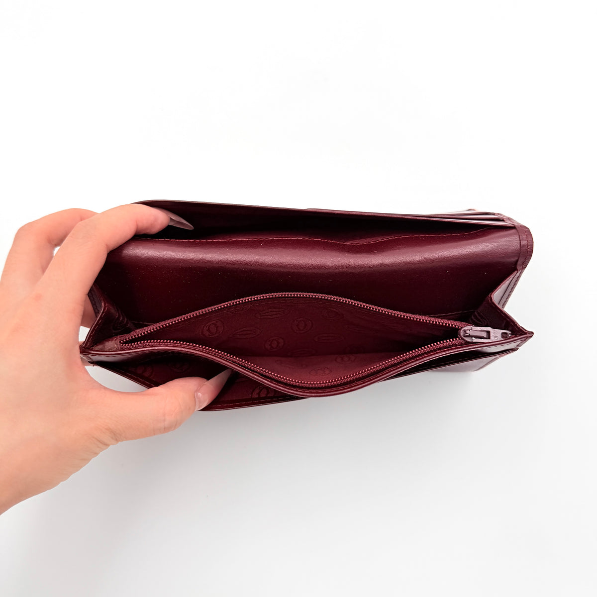 Cartier Must de Cartier bifold long wallet in burgundy leather with gold-tone corners.
