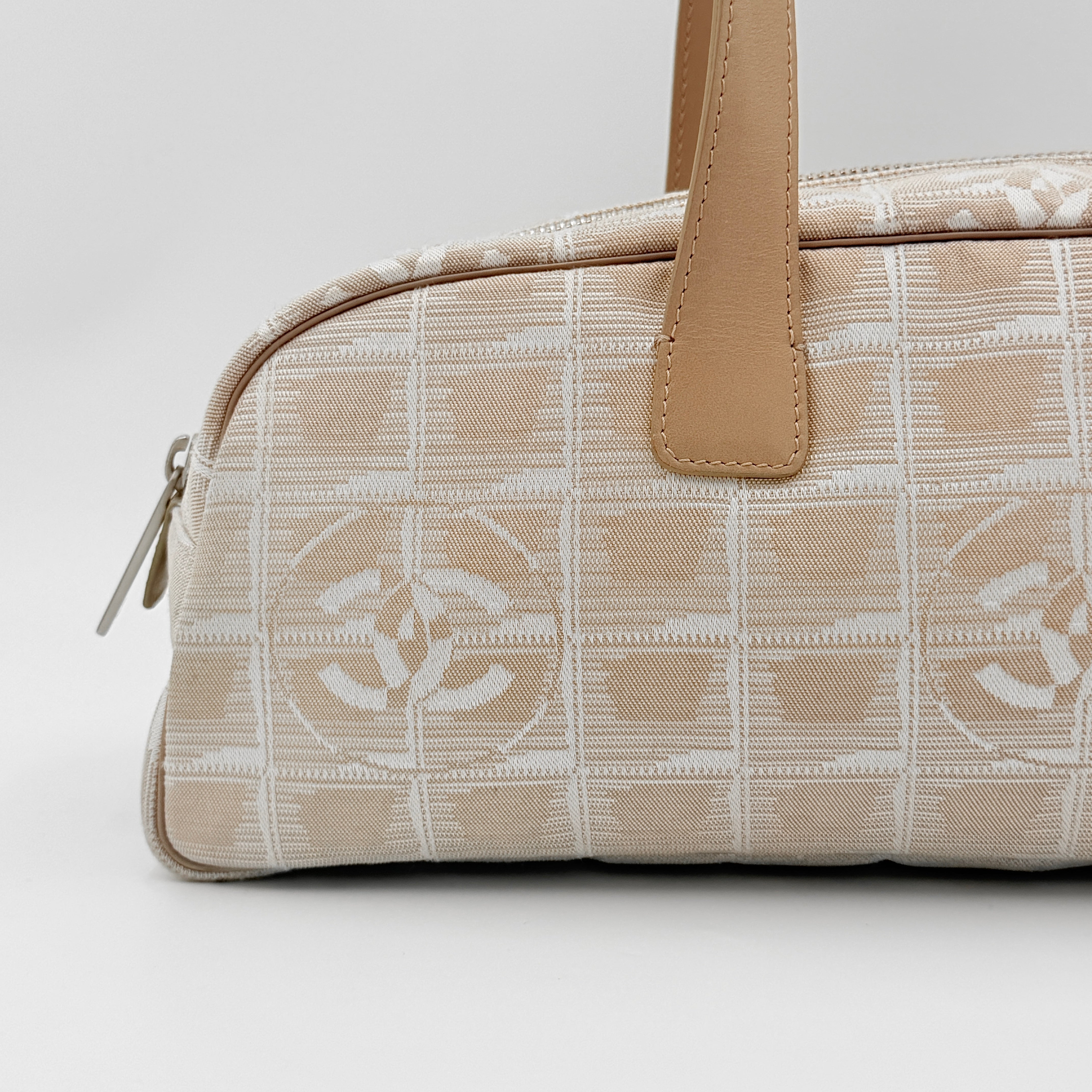 Chanel Travel Mini Boston Bag in beige nylon with CC motif and tan leather handles, shown in front view.