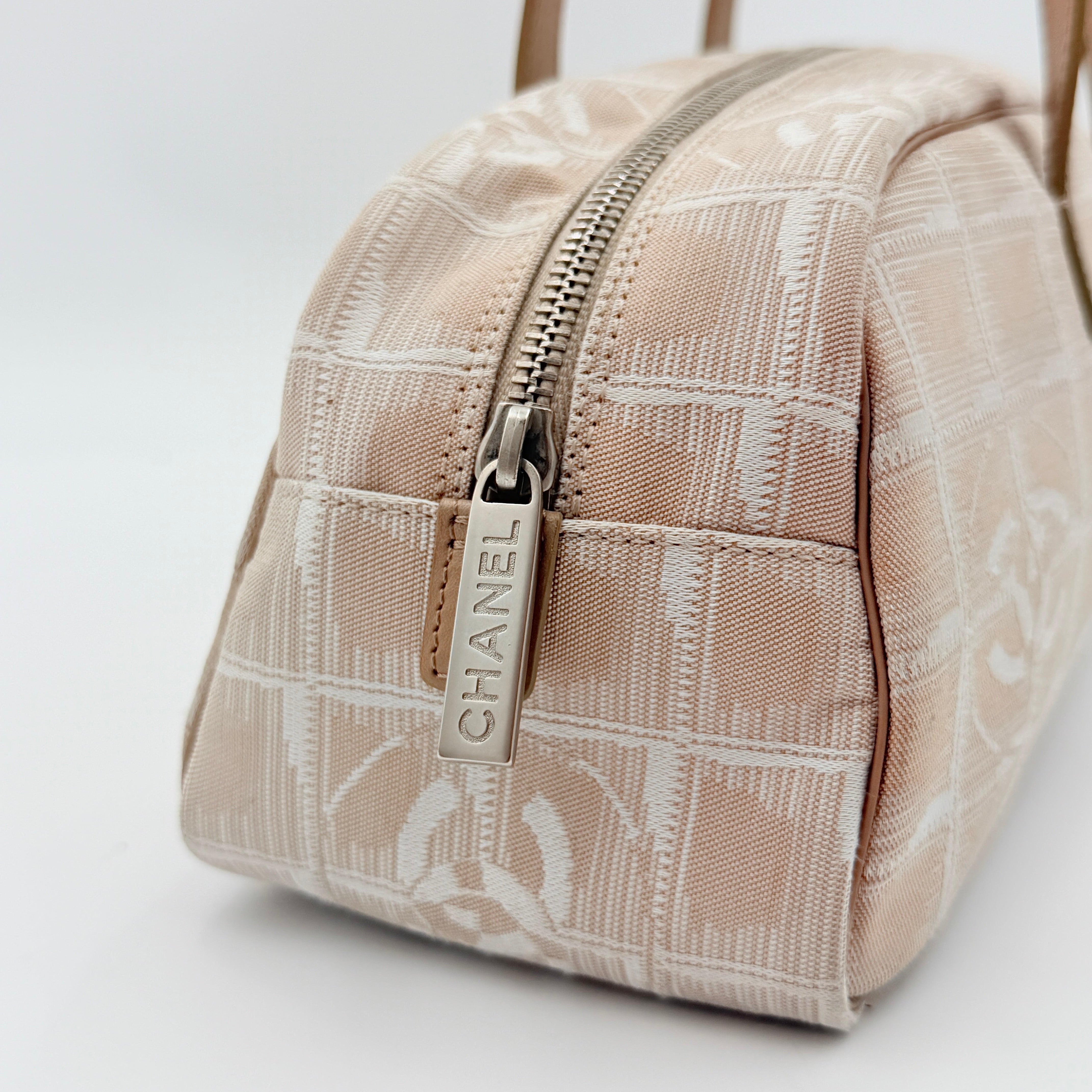 Chanel Travel Mini Boston Bag in beige nylon with CC motif and tan leather handles, shown in front view.