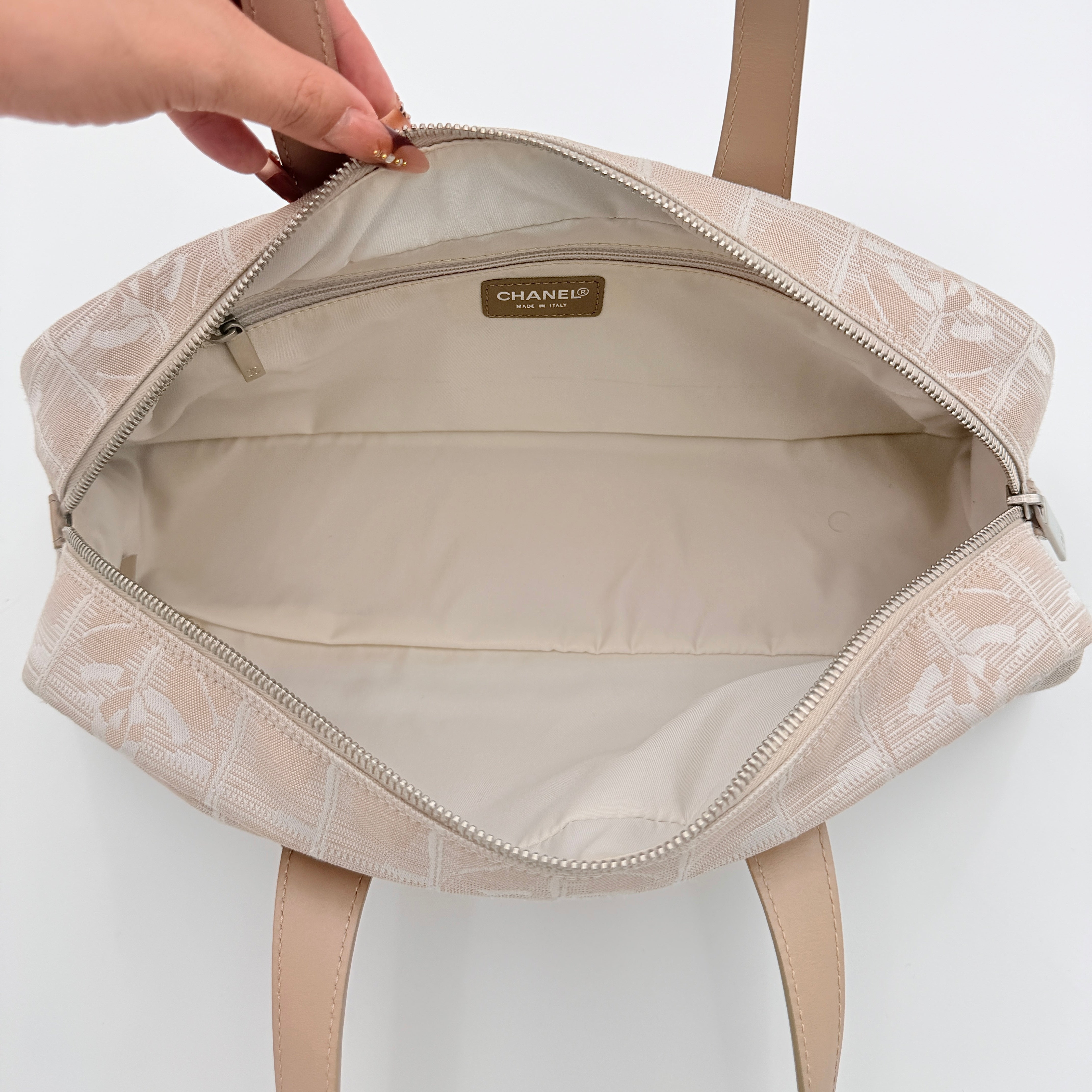 Chanel Travel Mini Boston Bag in beige nylon with CC motif and tan leather handles, shown in front view.