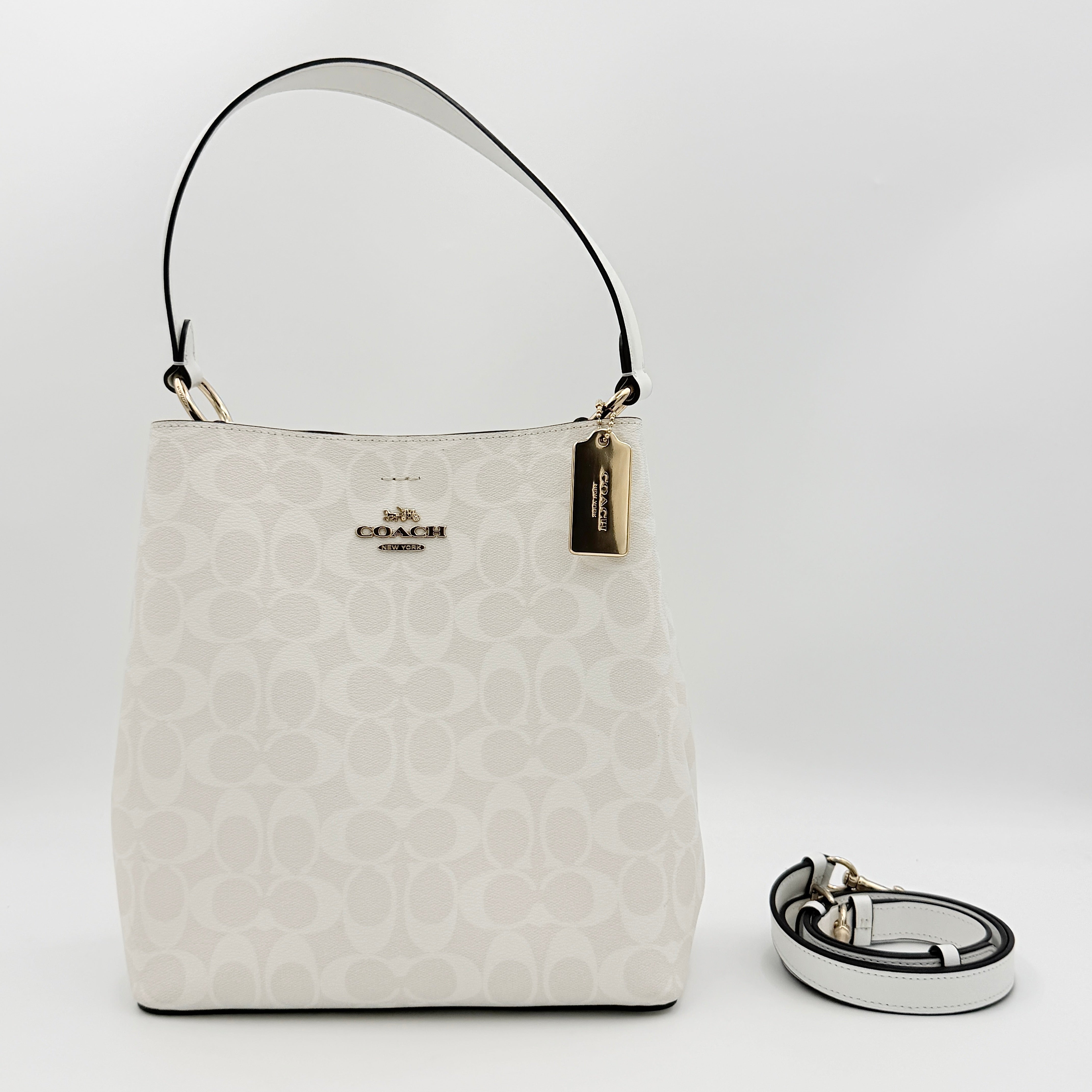 Coach Signature Town Bucket Shoulder Bag in white monogram canvas, shown with detachable strap and gold-tone hardware.