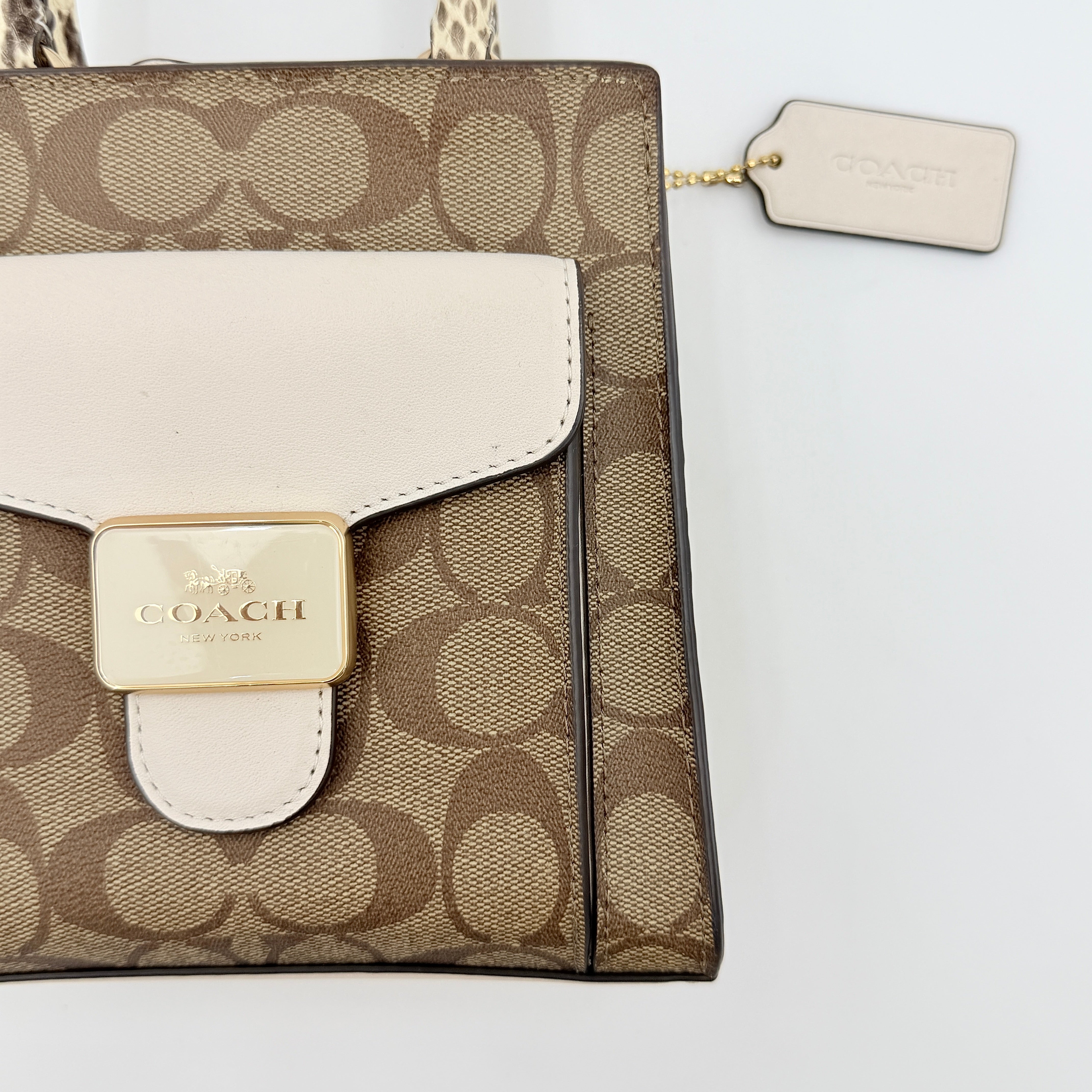 Coach Mini Pepper HandBag in beige canvas with white leather and snakeskin-effect handle, styled with detachable crossbody strap.