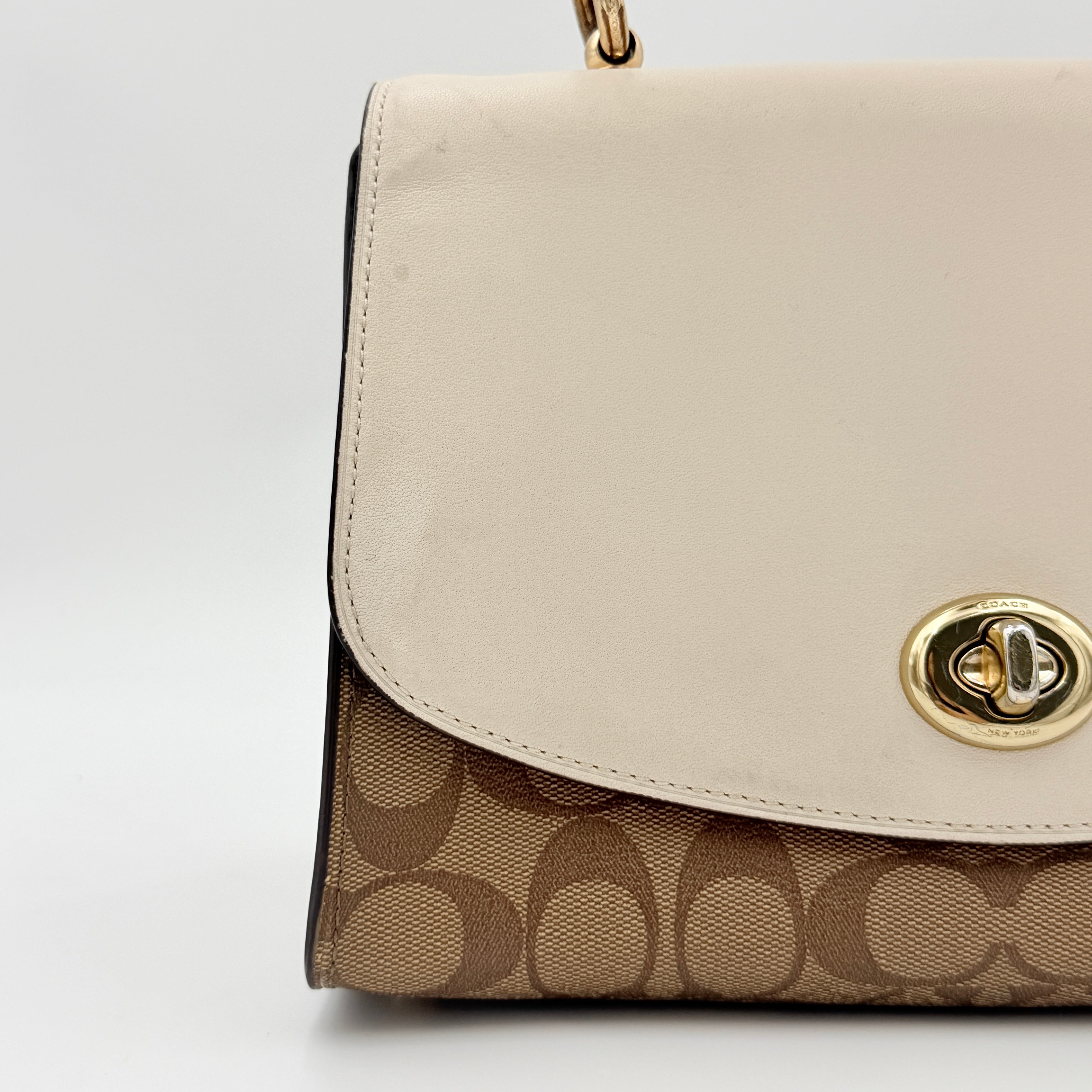 Coach Signature Tilly Top Handle Bag in beige and white with gold-tone hardware and detachable strap, displayed against a clean background.