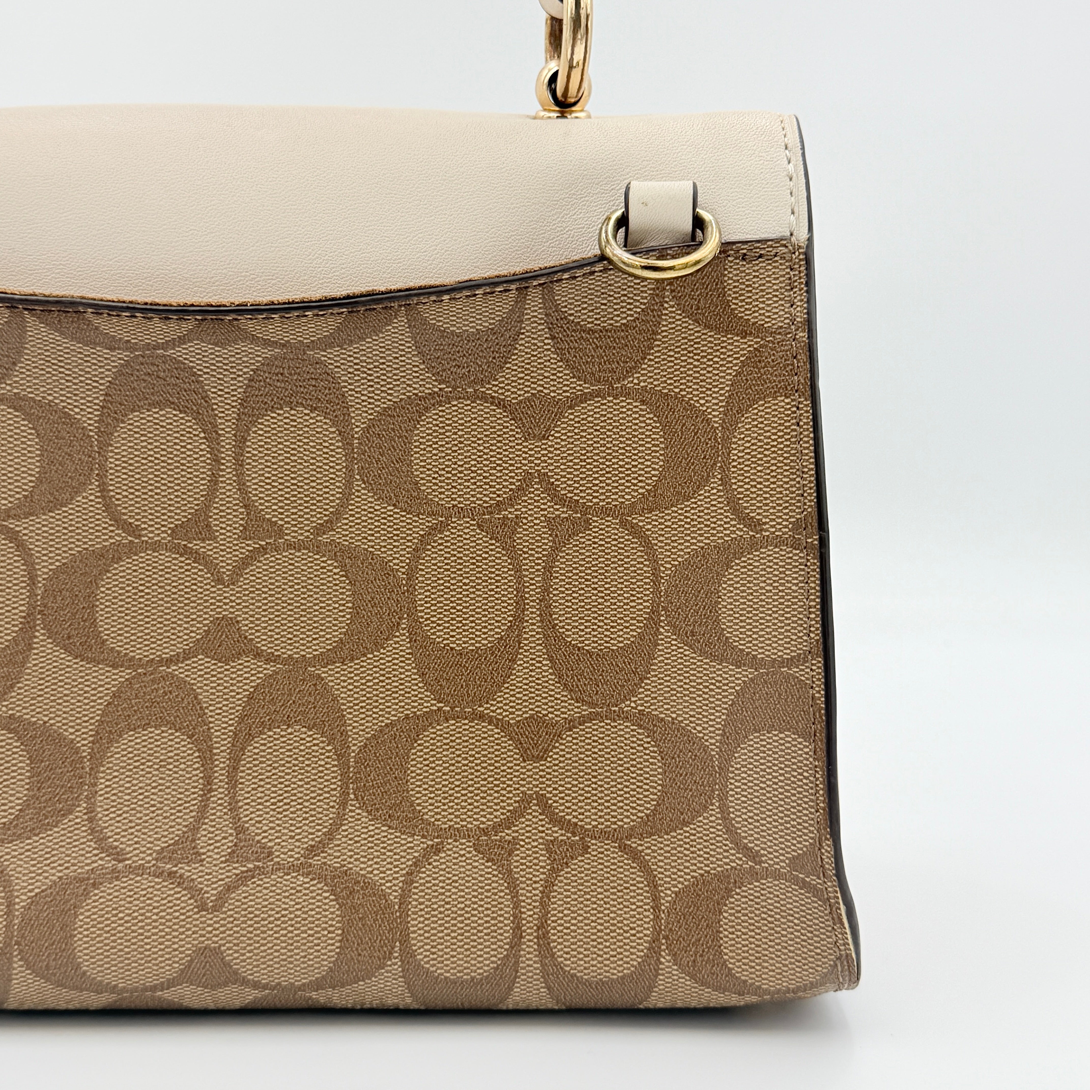 Coach Signature Tilly Top Handle Bag in beige and white with gold-tone hardware and detachable strap, displayed against a clean background.
