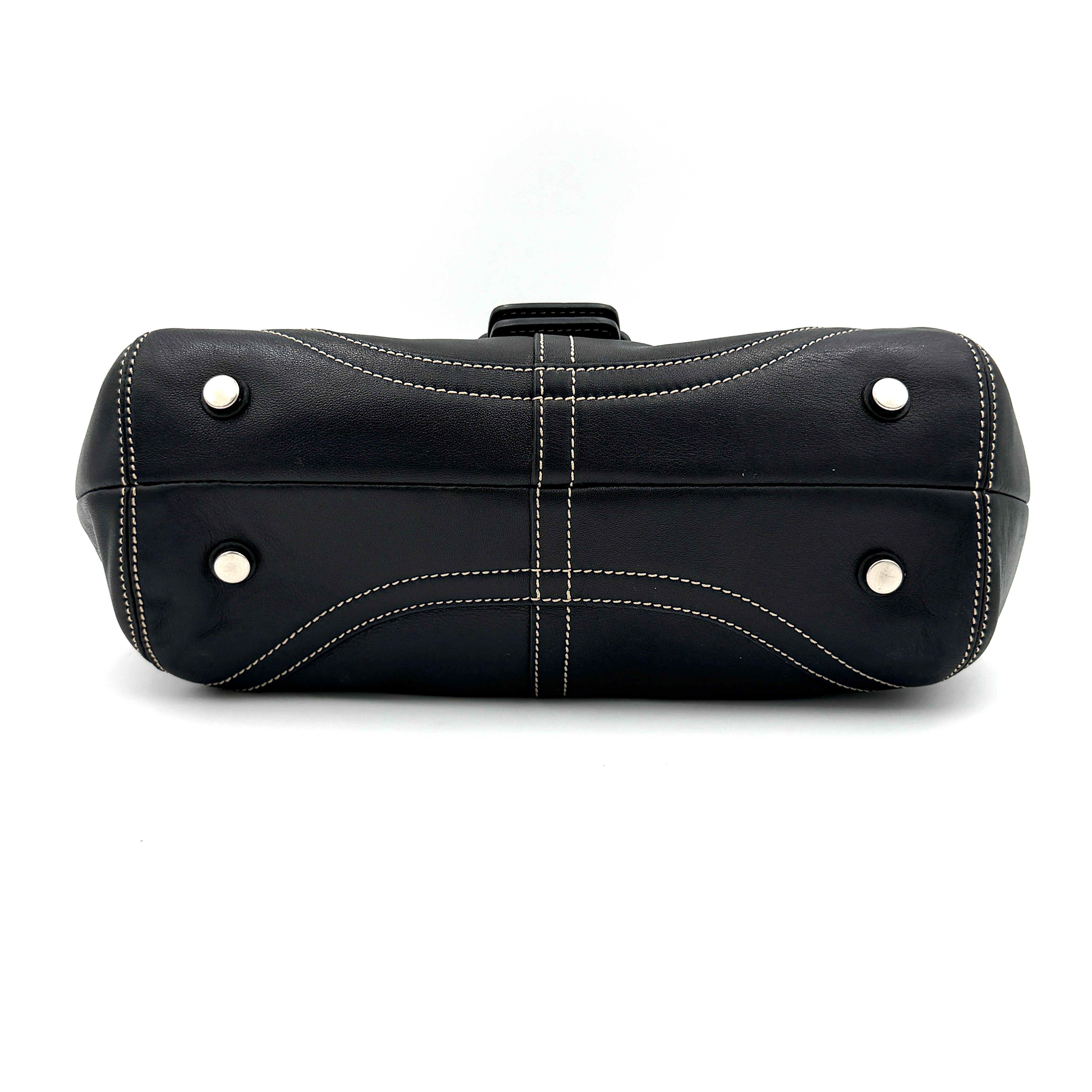 Coach Soho Buckle Top Handle Bag in black leather with contrast stitching and silver buckle, presented against a white background.