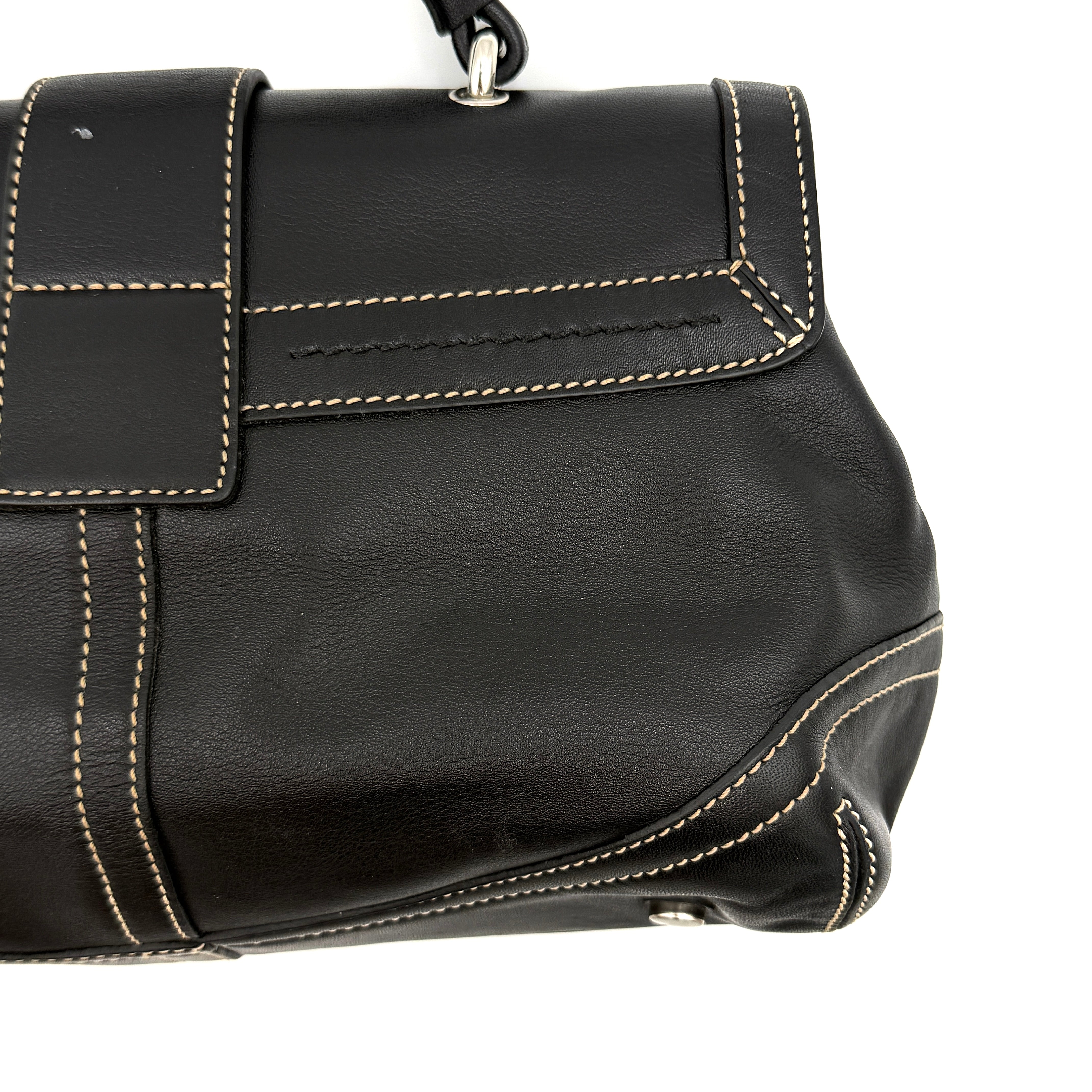 Coach Soho Buckle Top Handle Bag in black leather with contrast stitching and silver buckle, presented against a white background.
