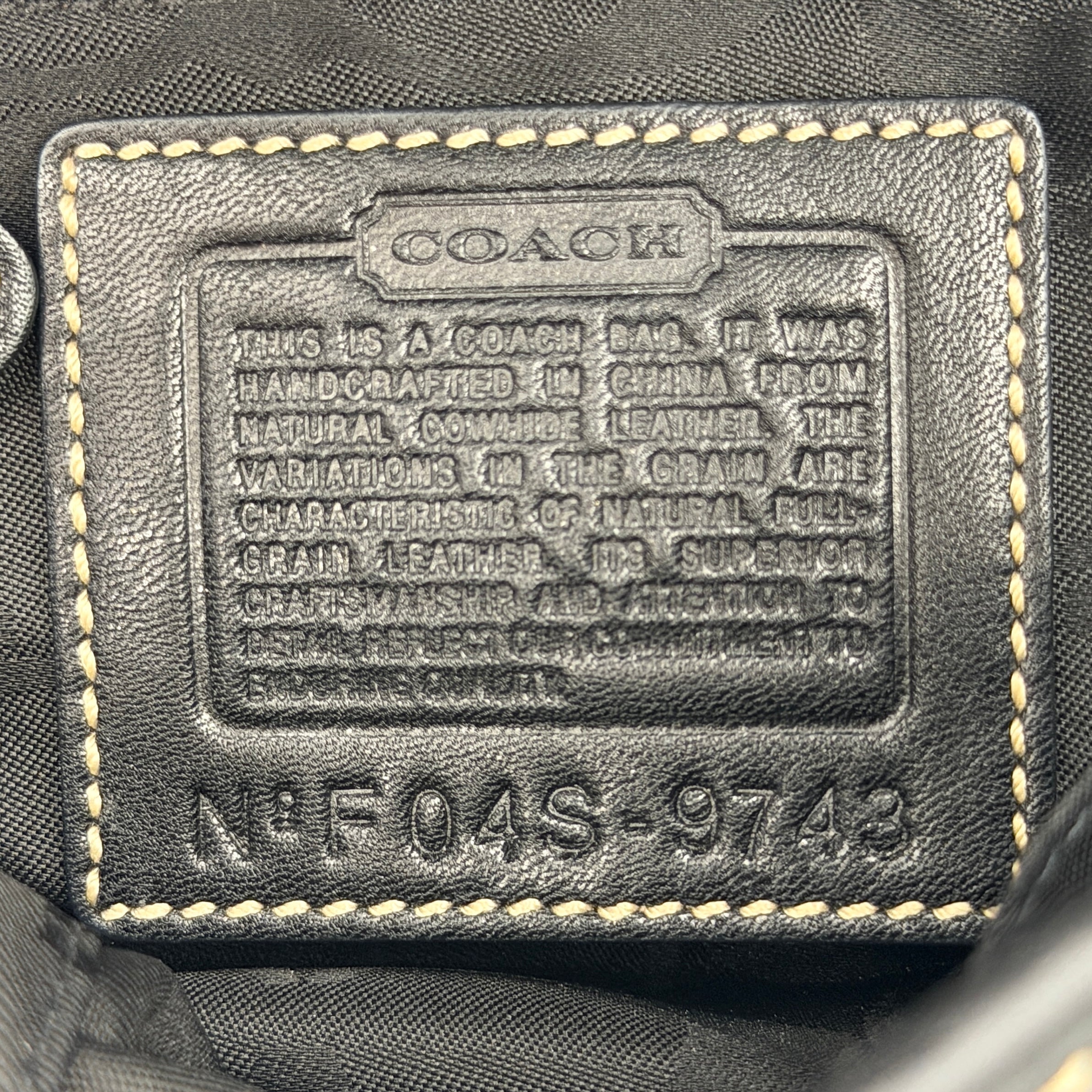 Coach Soho Buckle Top Handle Bag in black leather with contrast stitching and silver buckle, presented against a white background.