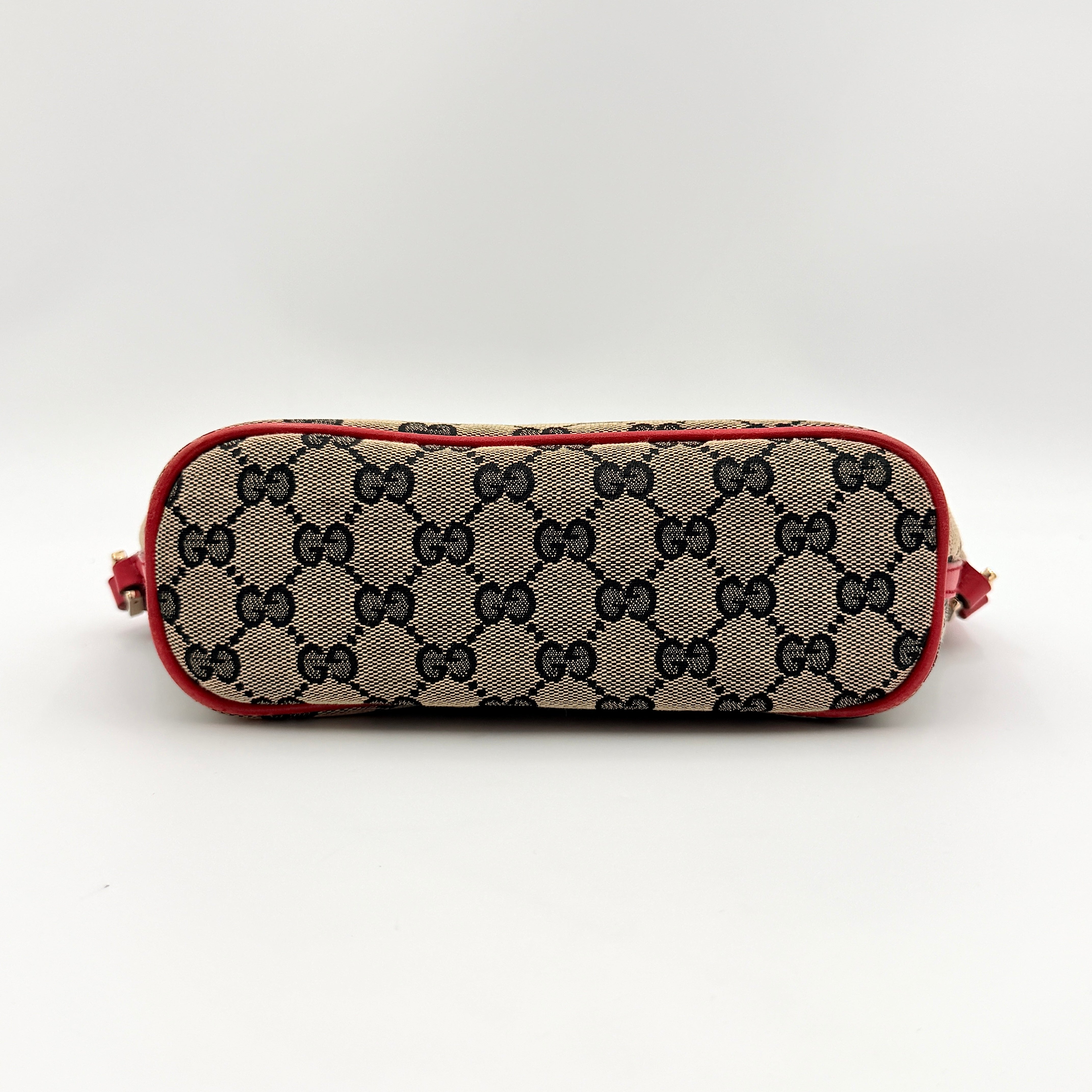 Gucci GG Monogram Pochette Boat Shoulder Bag in grey canvas with red leather trim and gold plaque, shown against a plain background.