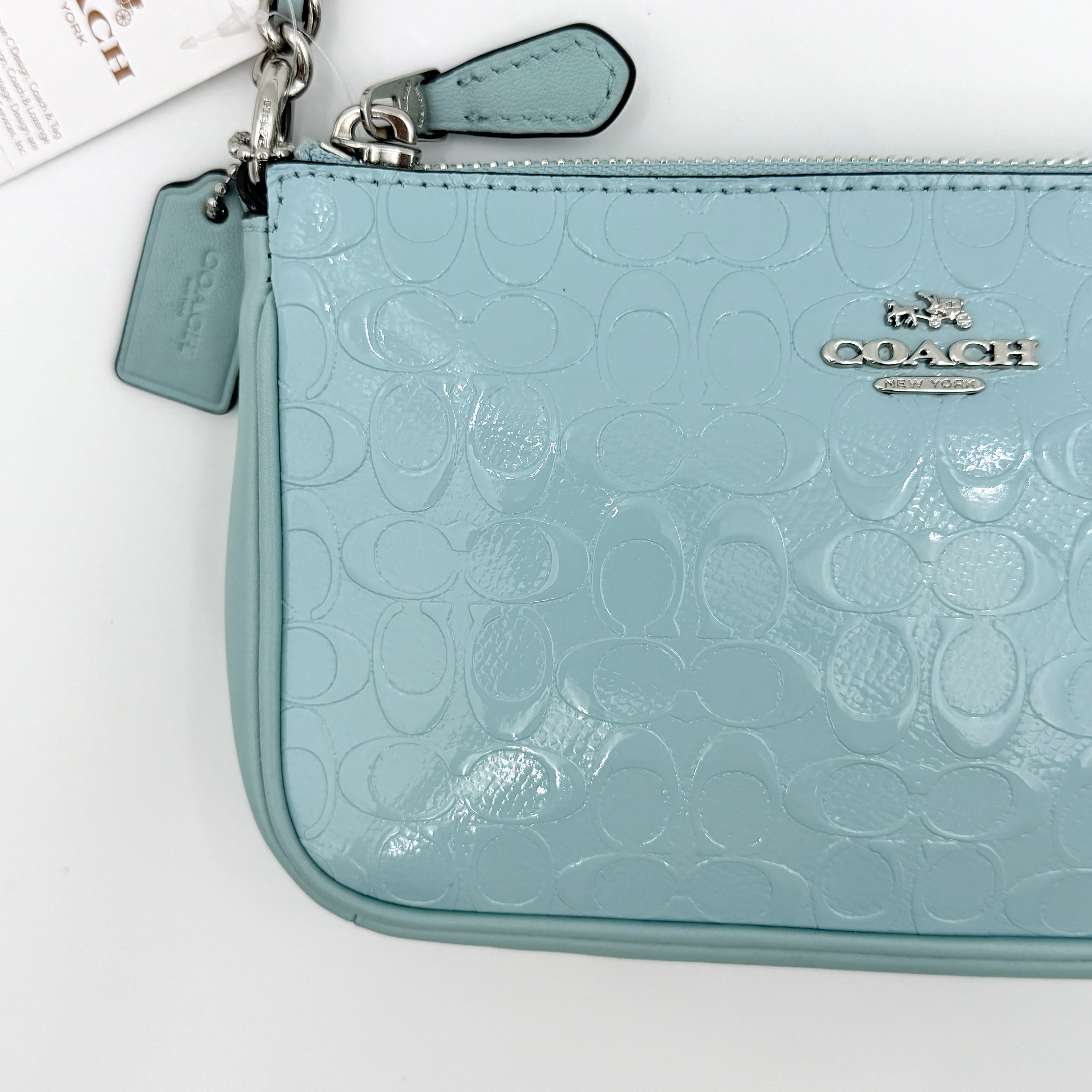 Coach Nolita 19 small shoulder bag in light blue embossed patent leather with silver-tone chain strap shown against a white background.