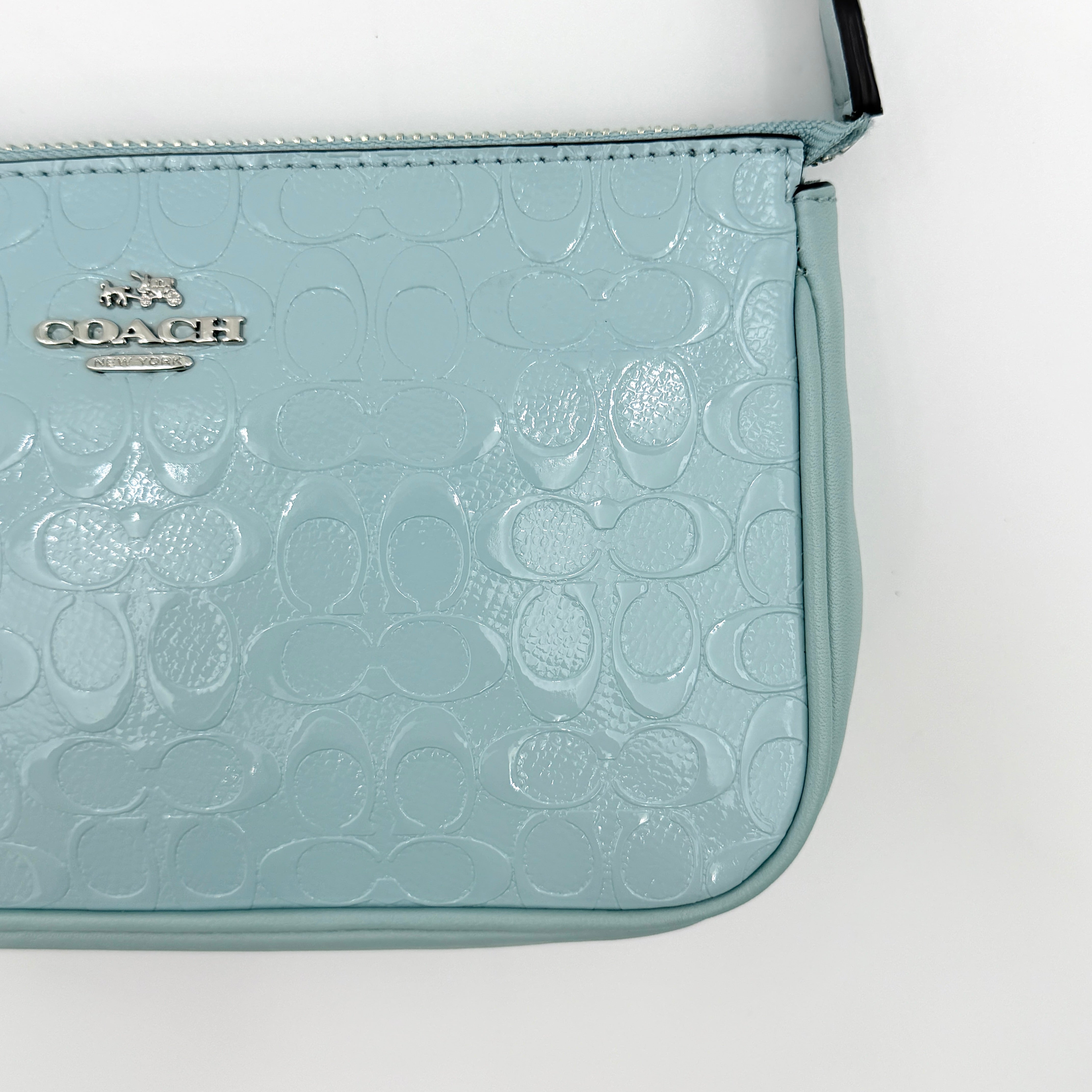 Coach Nolita 19 small shoulder bag in light blue embossed patent leather with silver-tone chain strap shown against a white background.