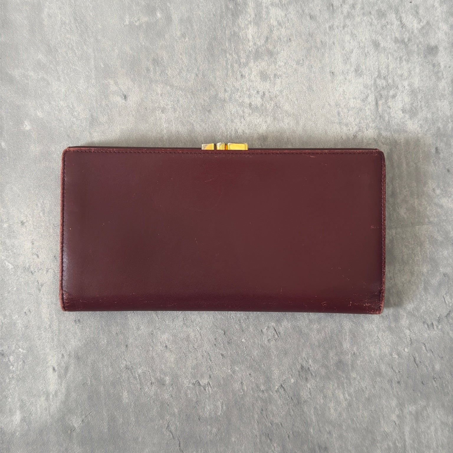 Cartier Must de Cartier trifold continental wallet in burgundy leather, showcasing detailed craftsmanship, gold-tone Cartier logo, and an organized interior.