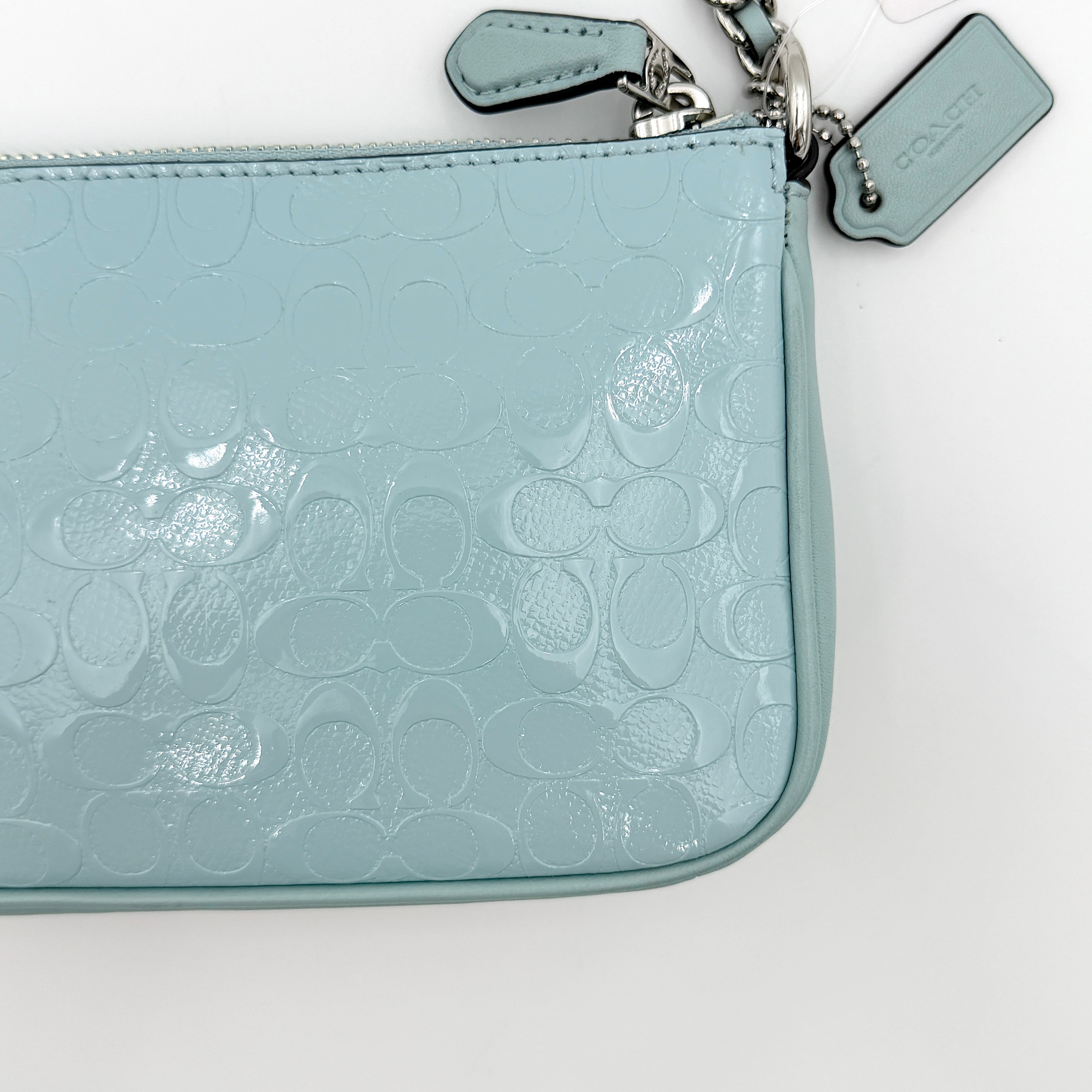 Coach Nolita 19 small shoulder bag in light blue embossed patent leather with silver-tone chain strap shown against a white background.