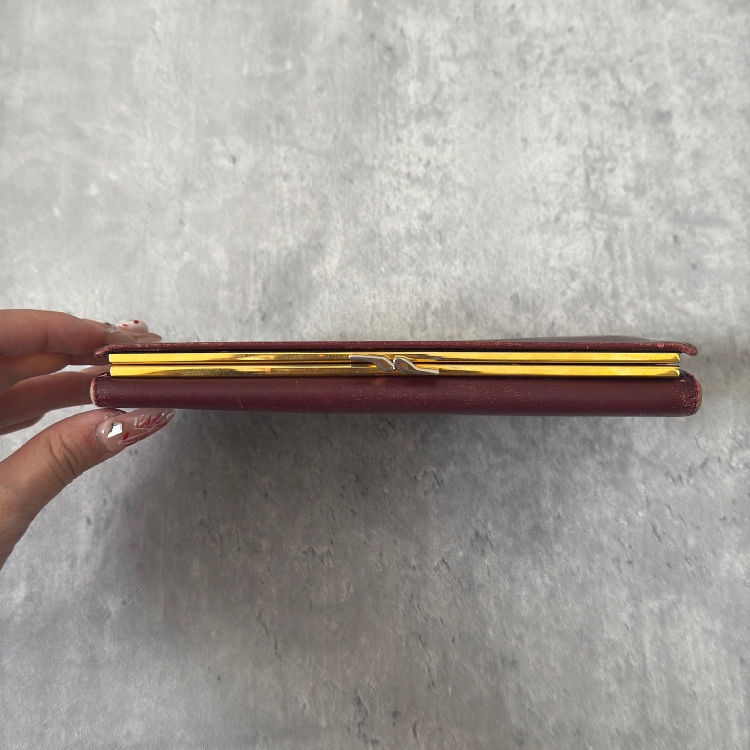 Cartier Must de Cartier trifold continental wallet in burgundy leather, showcasing detailed craftsmanship, gold-tone Cartier logo, and an organized interior.