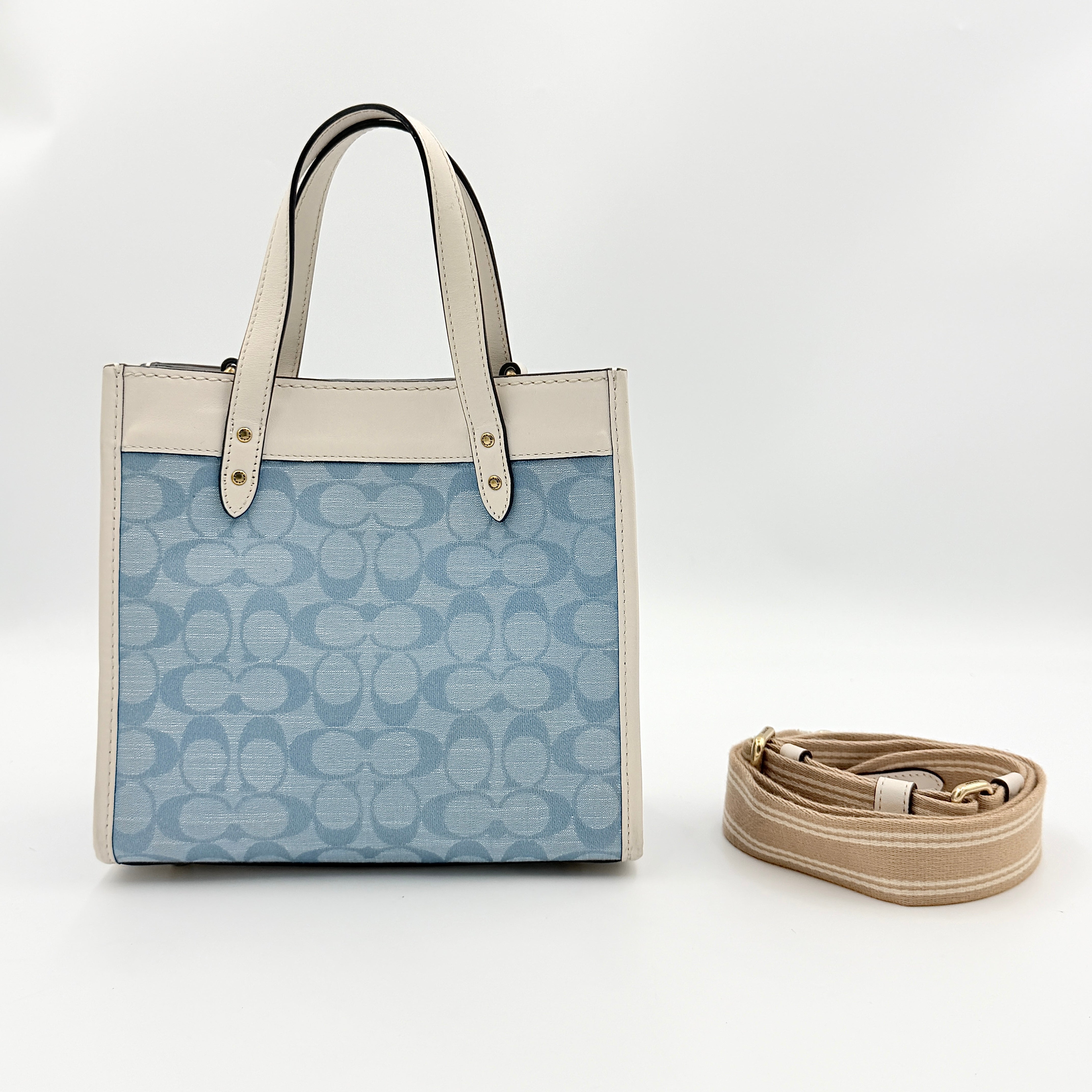Coach Field Tote 22 in blue signature jacquard with white leather trim and detachable strap, styled for versatile wear.