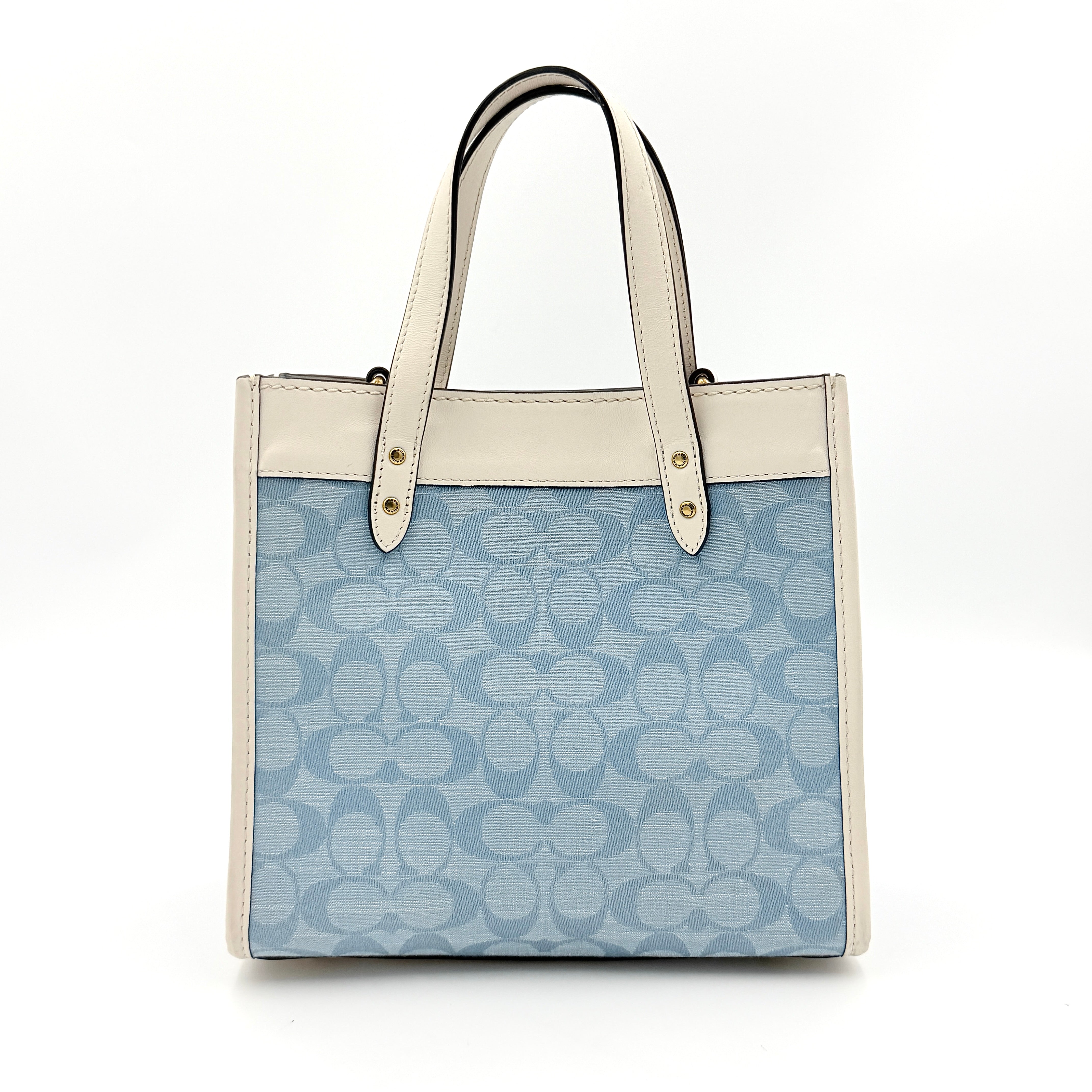 Coach Field Tote 22 in blue signature jacquard with white leather trim and detachable strap, styled for versatile wear.