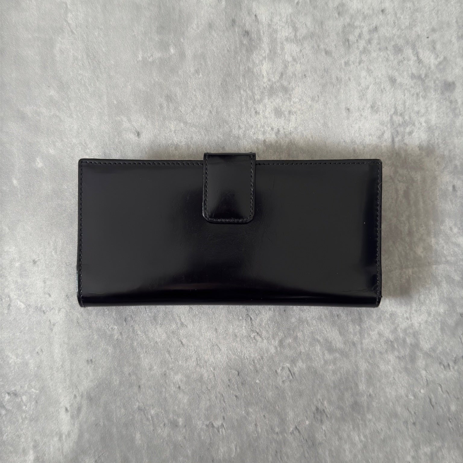 Gucci Continental Wallet in black patent leather, featuring a gold-tone Gucci logo, multiple card slots, and a spacious interior, epitomizes luxury and functionality.