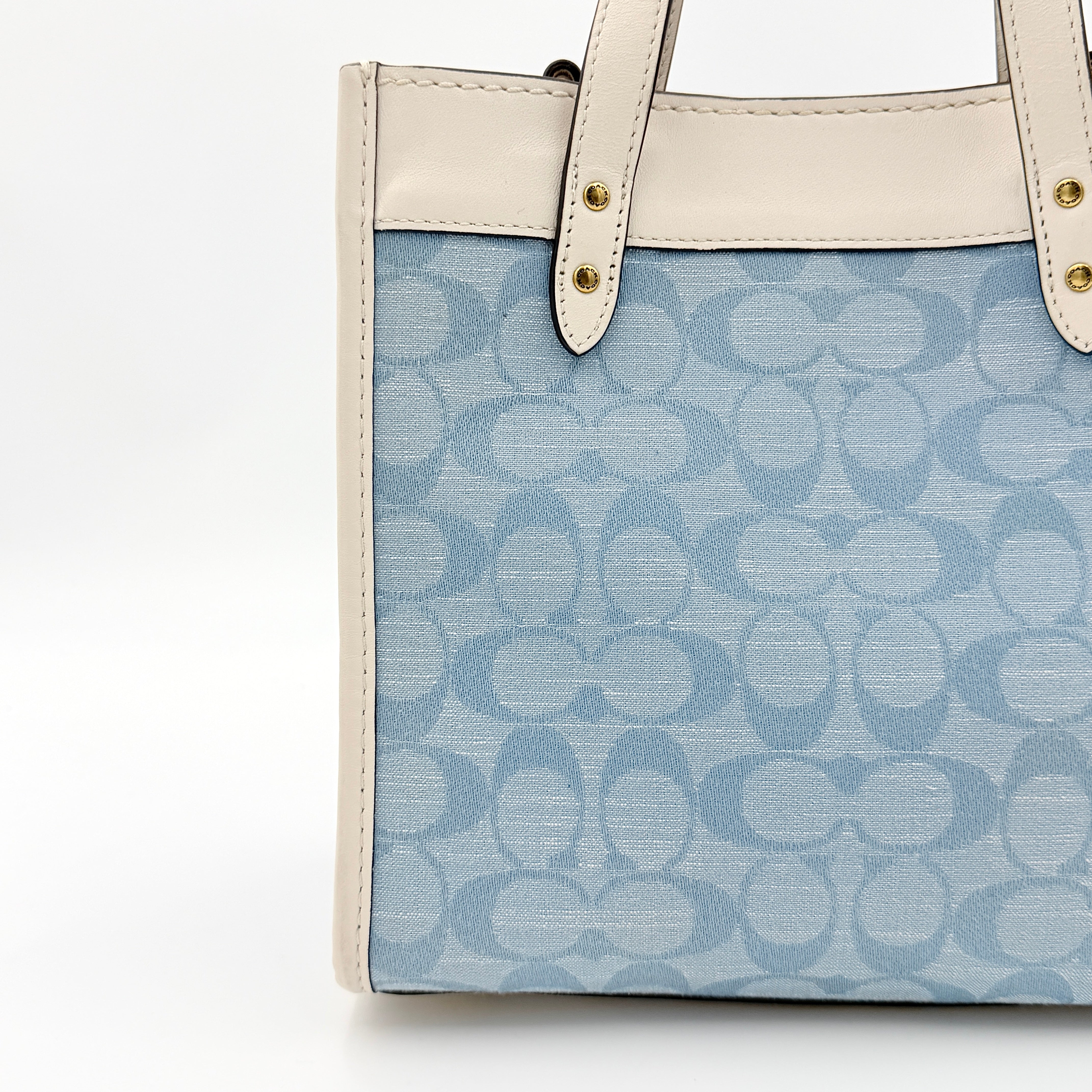 Coach Field Tote 22 in blue signature jacquard with white leather trim and detachable strap, styled for versatile wear.