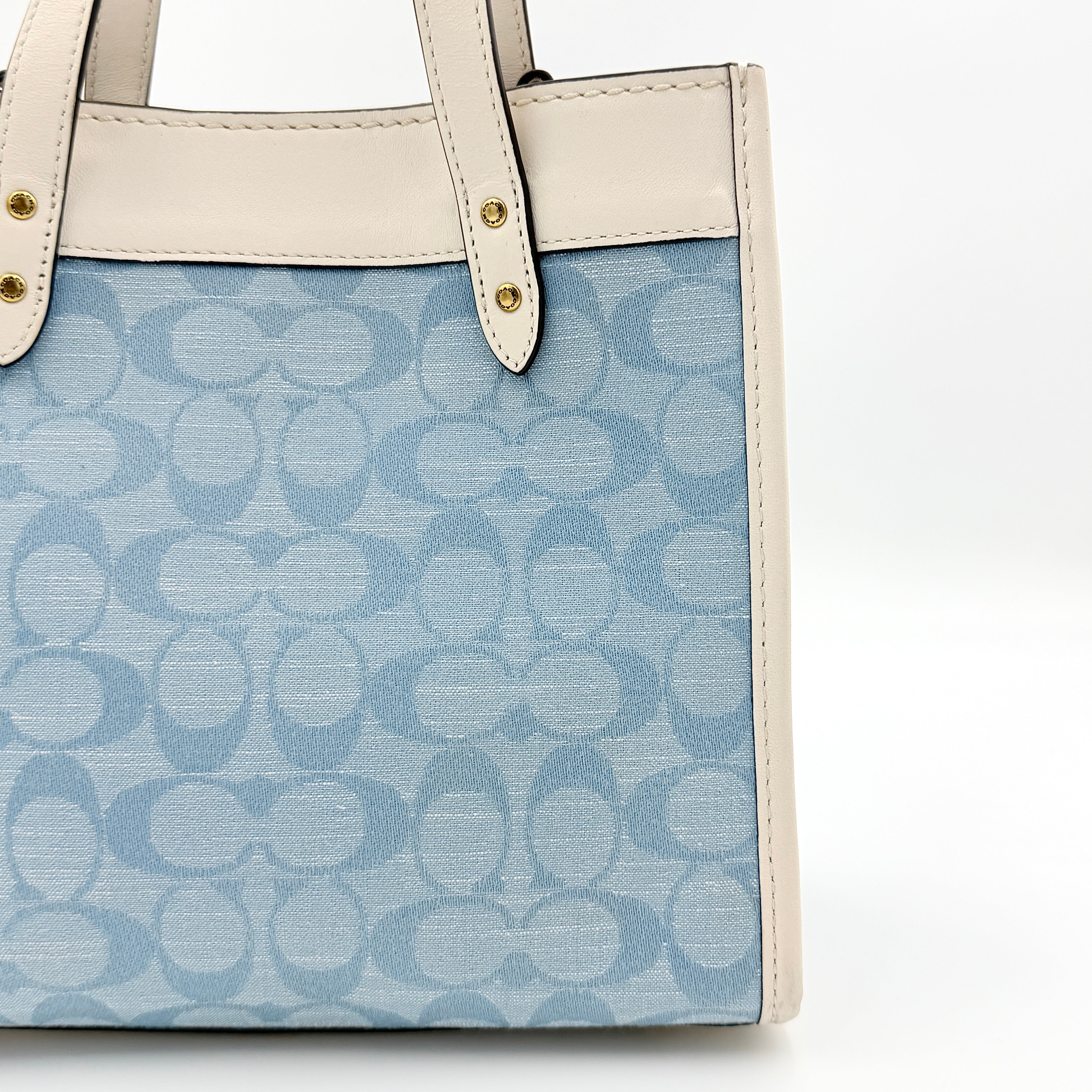 Coach Field Tote 22 in blue signature jacquard with white leather trim and detachable strap, styled for versatile wear.