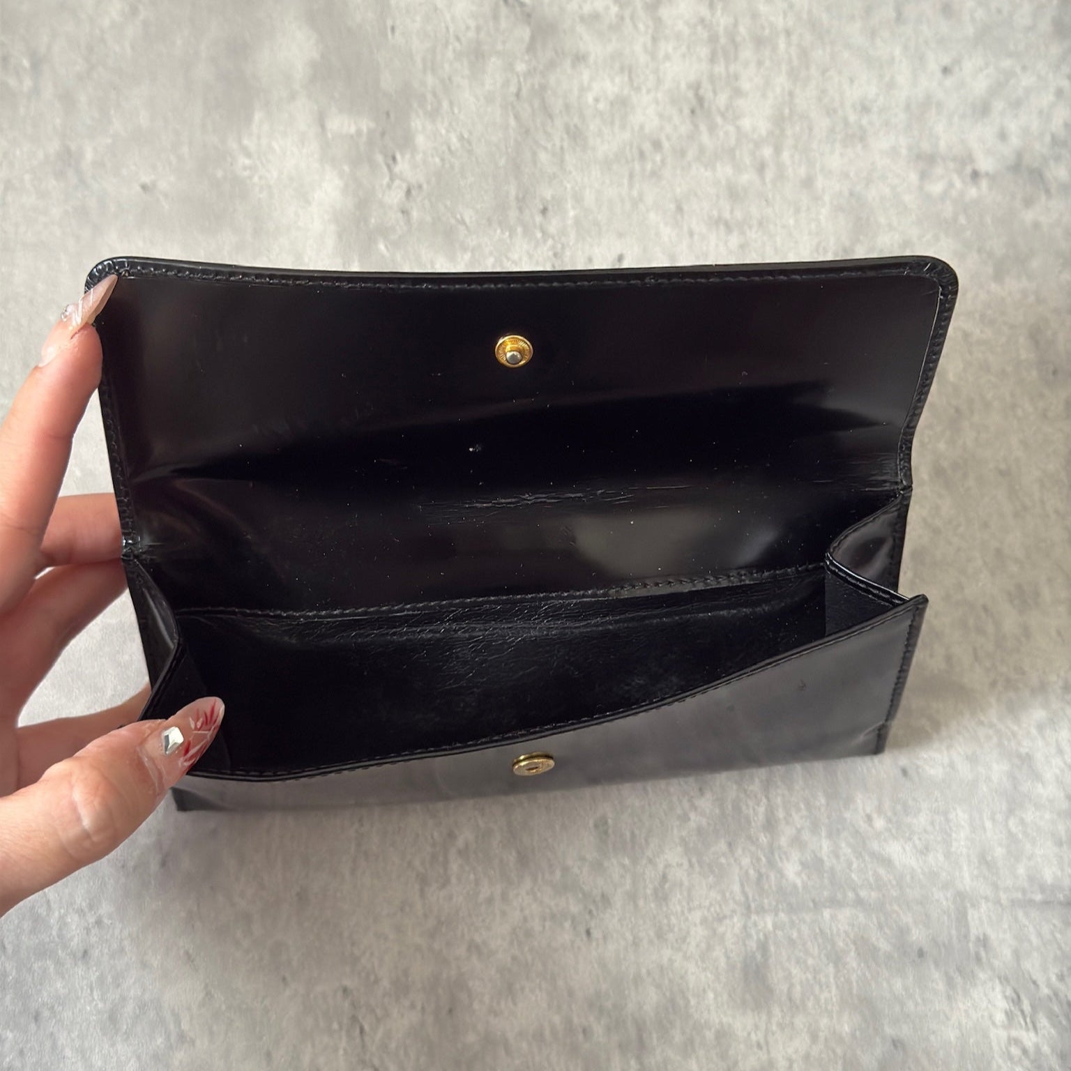 Gucci Continental Wallet in black patent leather, featuring a gold-tone Gucci logo, multiple card slots, and a spacious interior, epitomizes luxury and functionality.