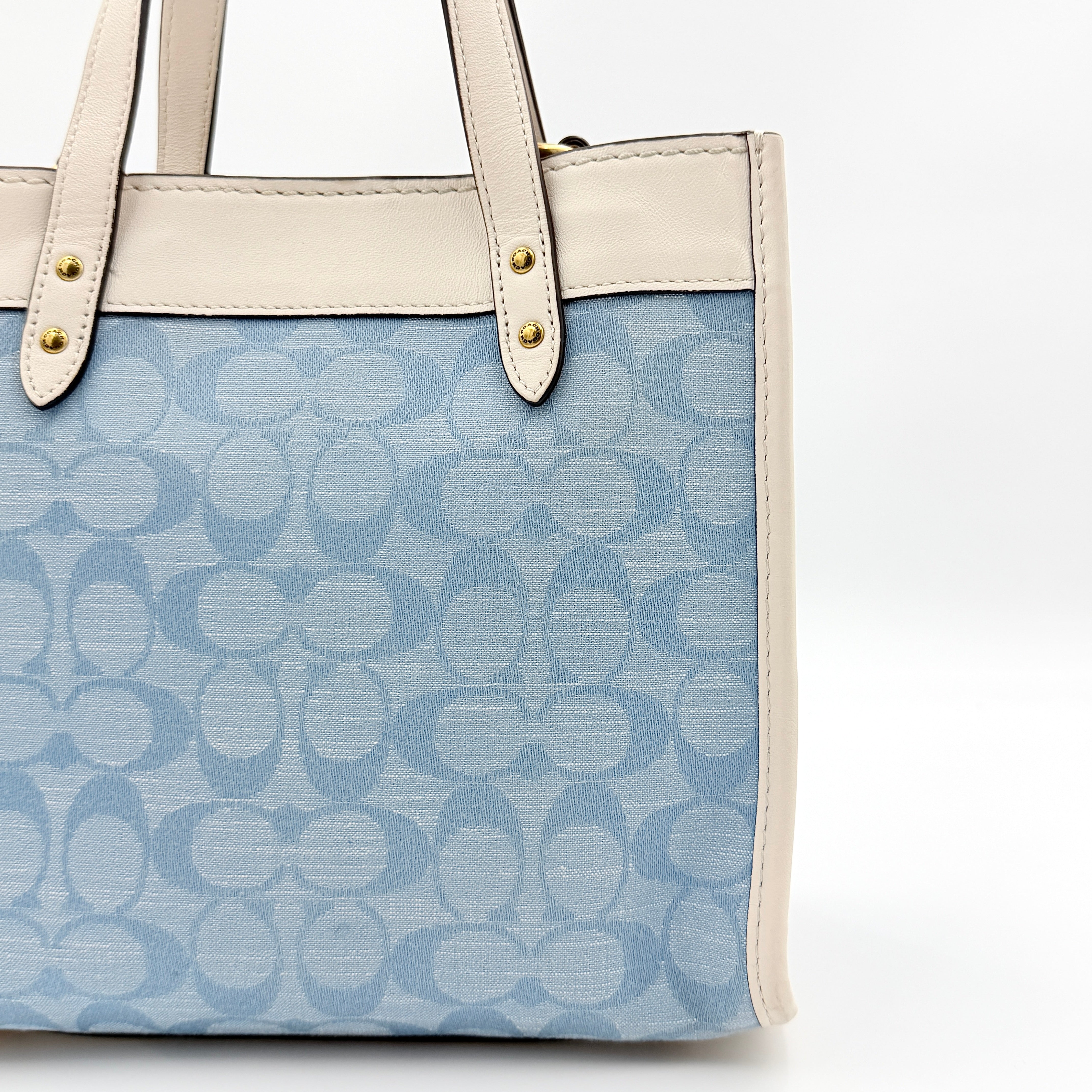 Coach Field Tote 22 in blue signature jacquard with white leather trim and detachable strap, styled for versatile wear.