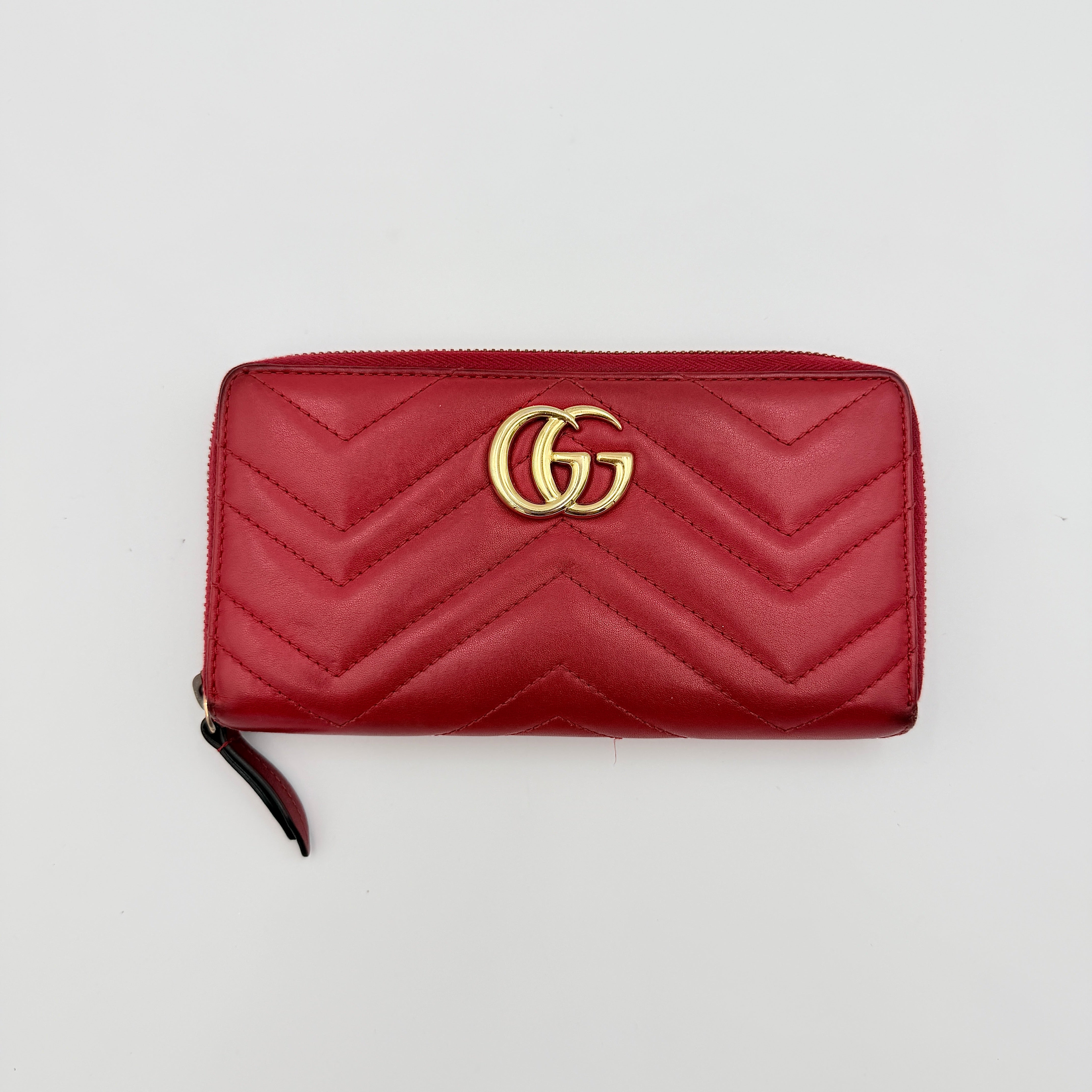 Gucci GG Marmont quilted long wallet in red leather with gold hardware displayed flat against a white background.