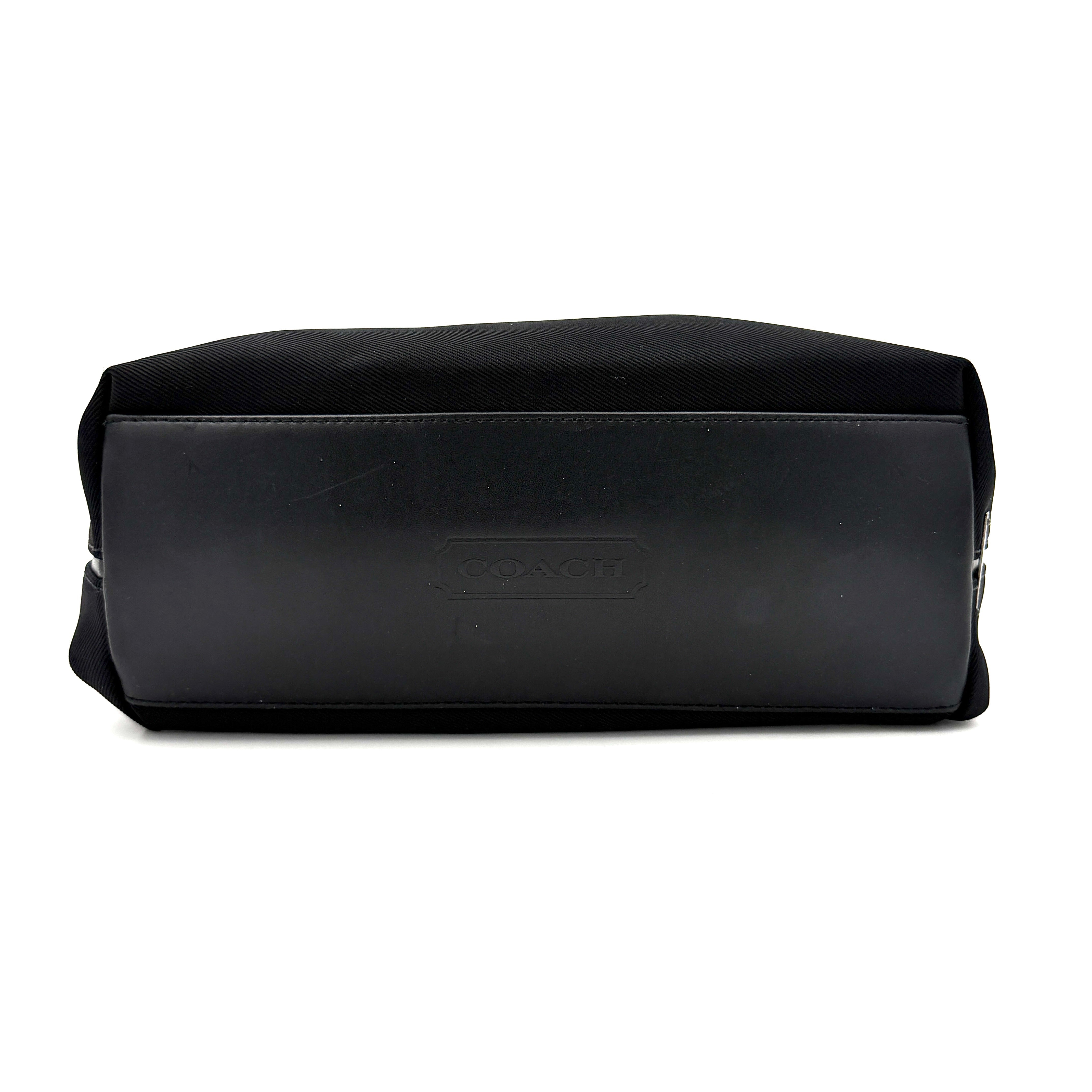 Coach Mercer Nylon Tote Bag in black with structured silhouette, leather handles, and subtle silver logo plaque at the base.