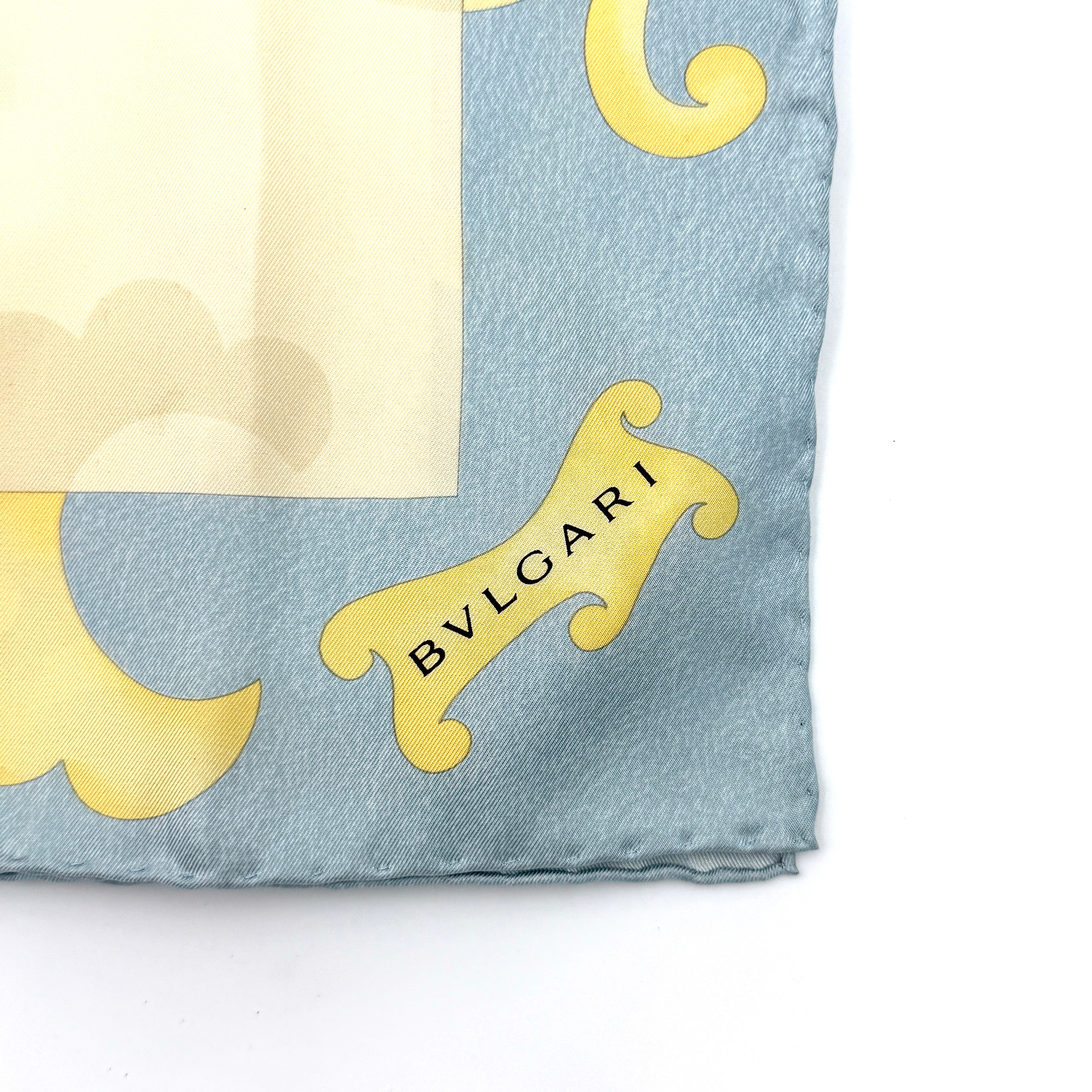Bvlgari silk scarf in light blue and cream, featuring playful accessory illustrations and baroque-style borders.