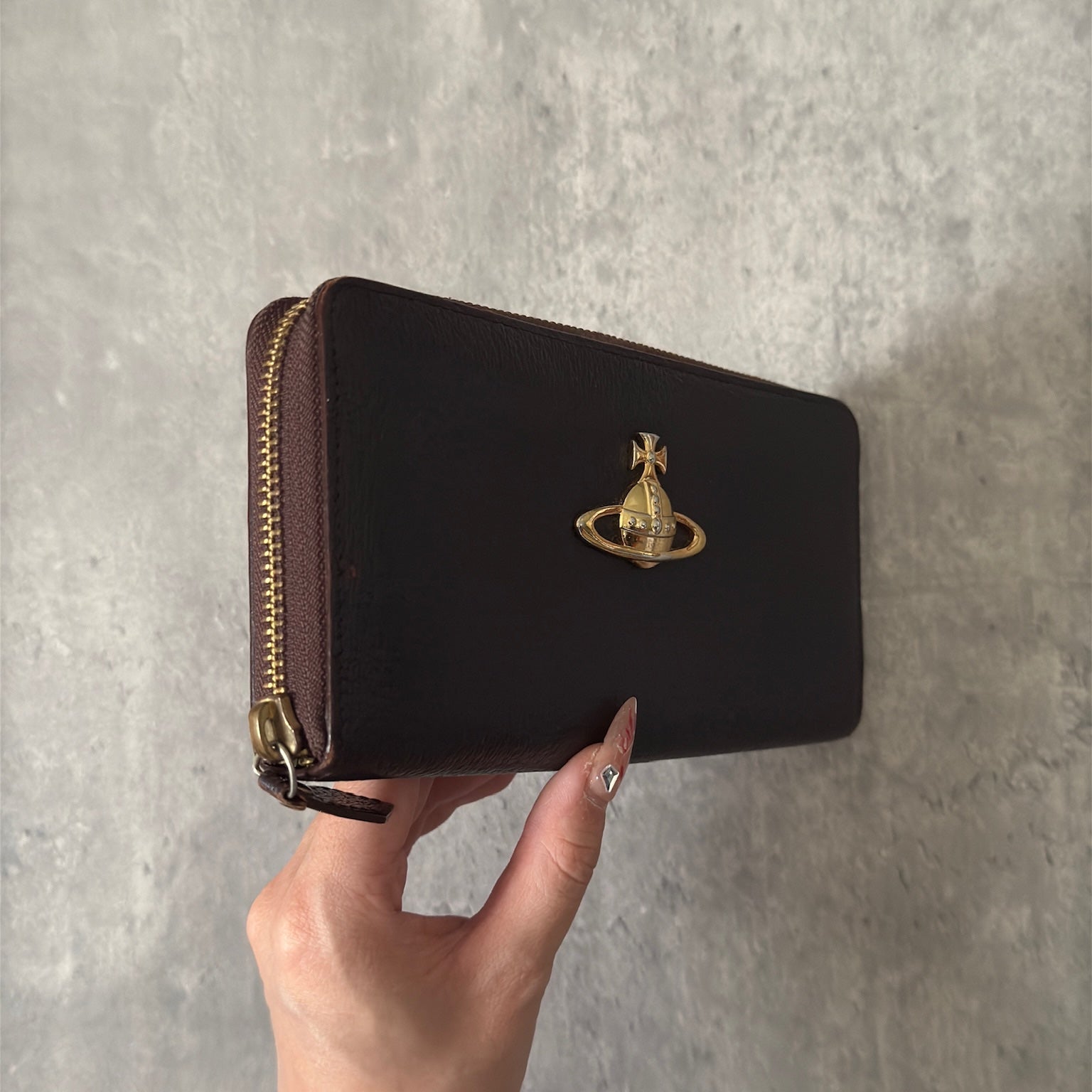 Vivienne Westwood Seditionaries Wallet, black leather, featuring the iconic gold-tone Orb emblem and a zip-around closure, interior detailed with brand's signature pattern.