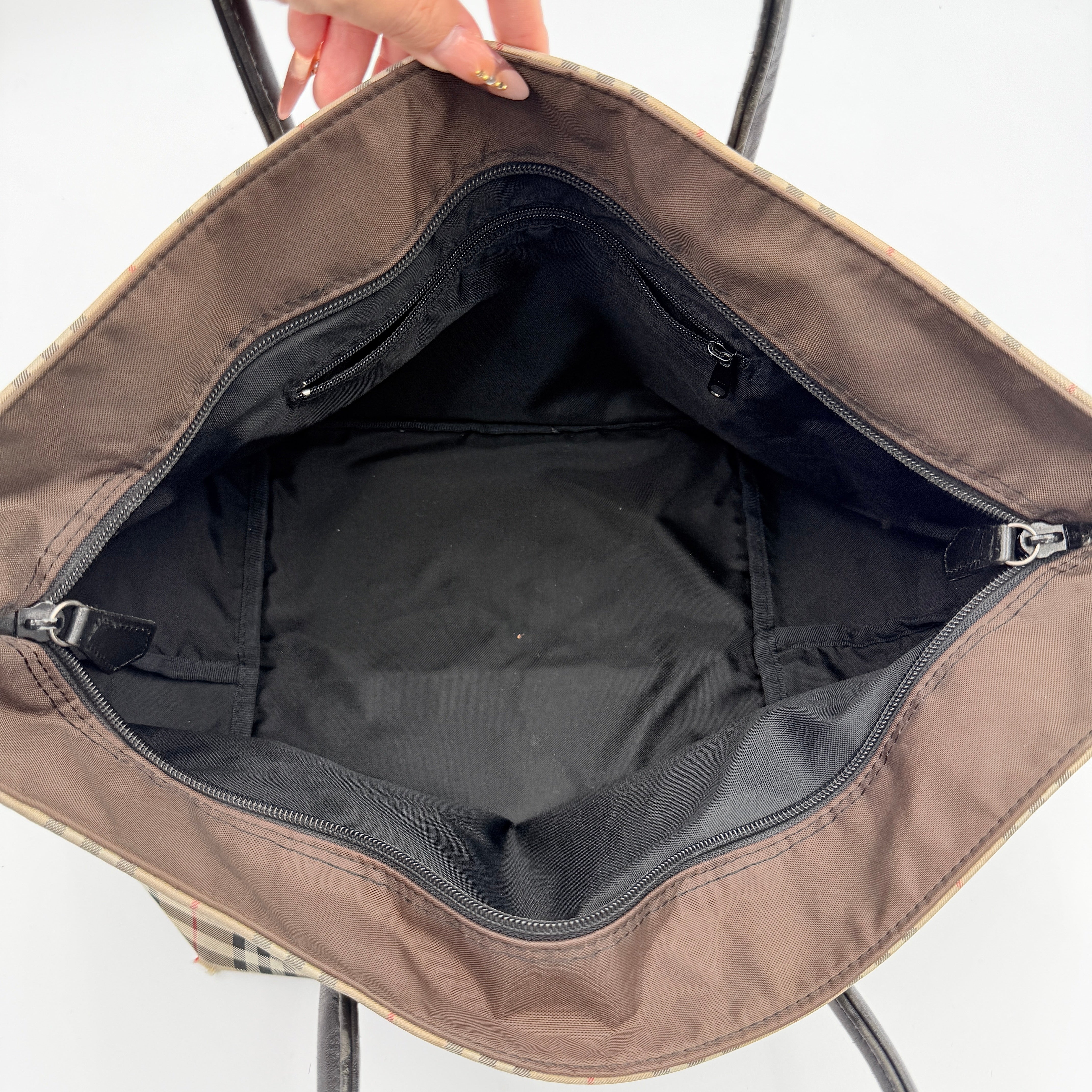 Burberry Nova Check shoulder bag in beige and black with black leather handles and zip closure.
