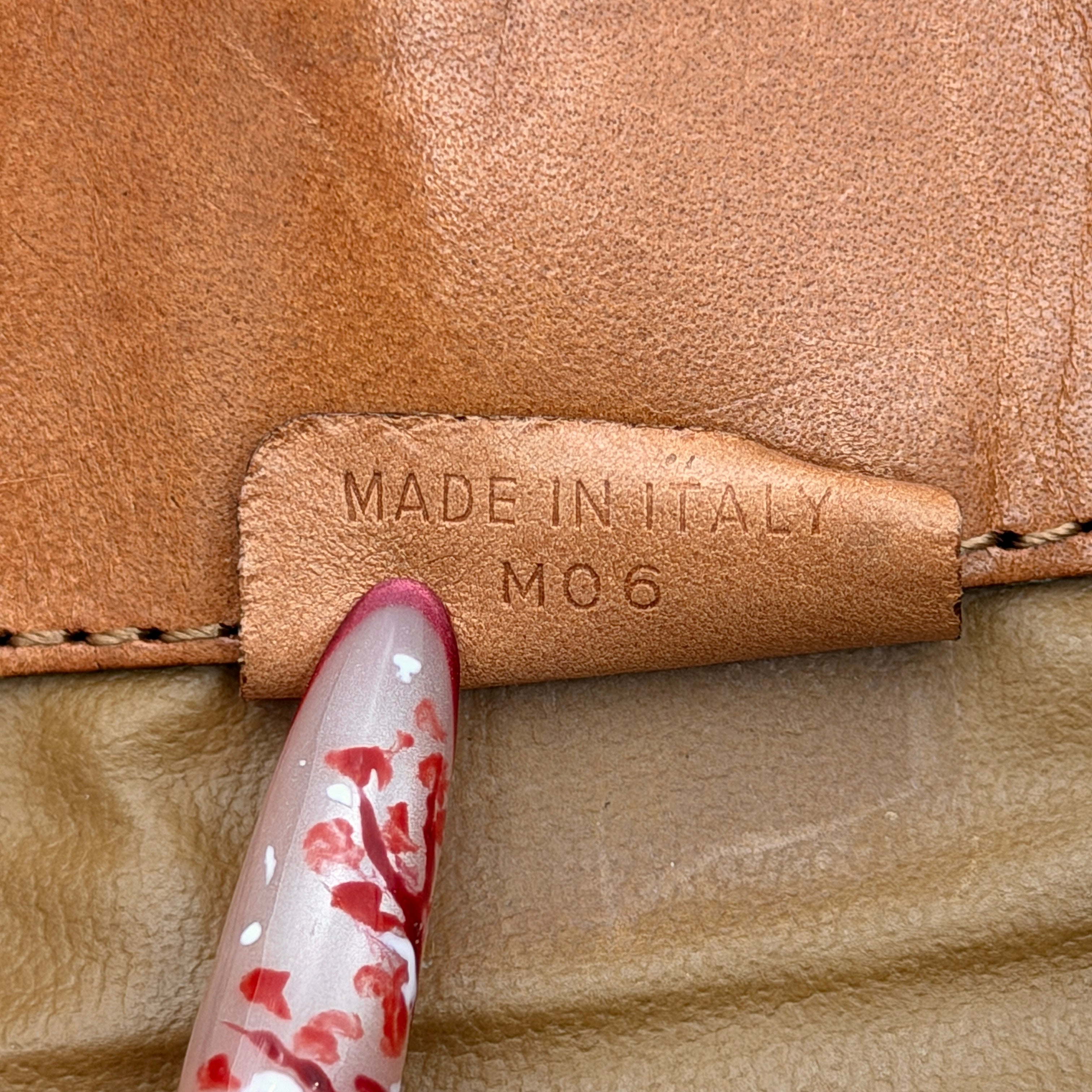 The Celine Macadam Clutch Bag in beige, featuring the iconic monogram canvas and tan leather trim, shown neatly closed with its signature emblem on the flap.