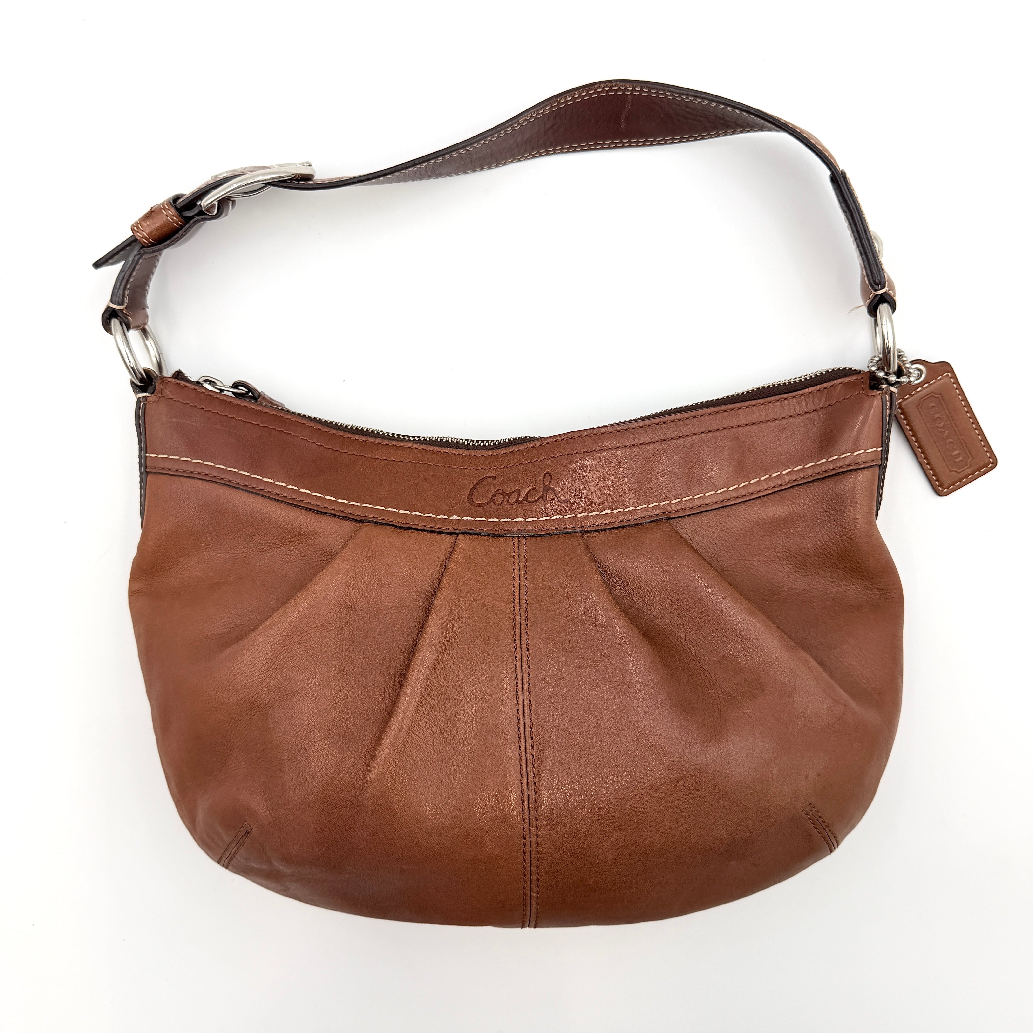 Coach Soho Hobo brown leather shoulder bag with pleated detailing and silver hardware, shown on a white background.
