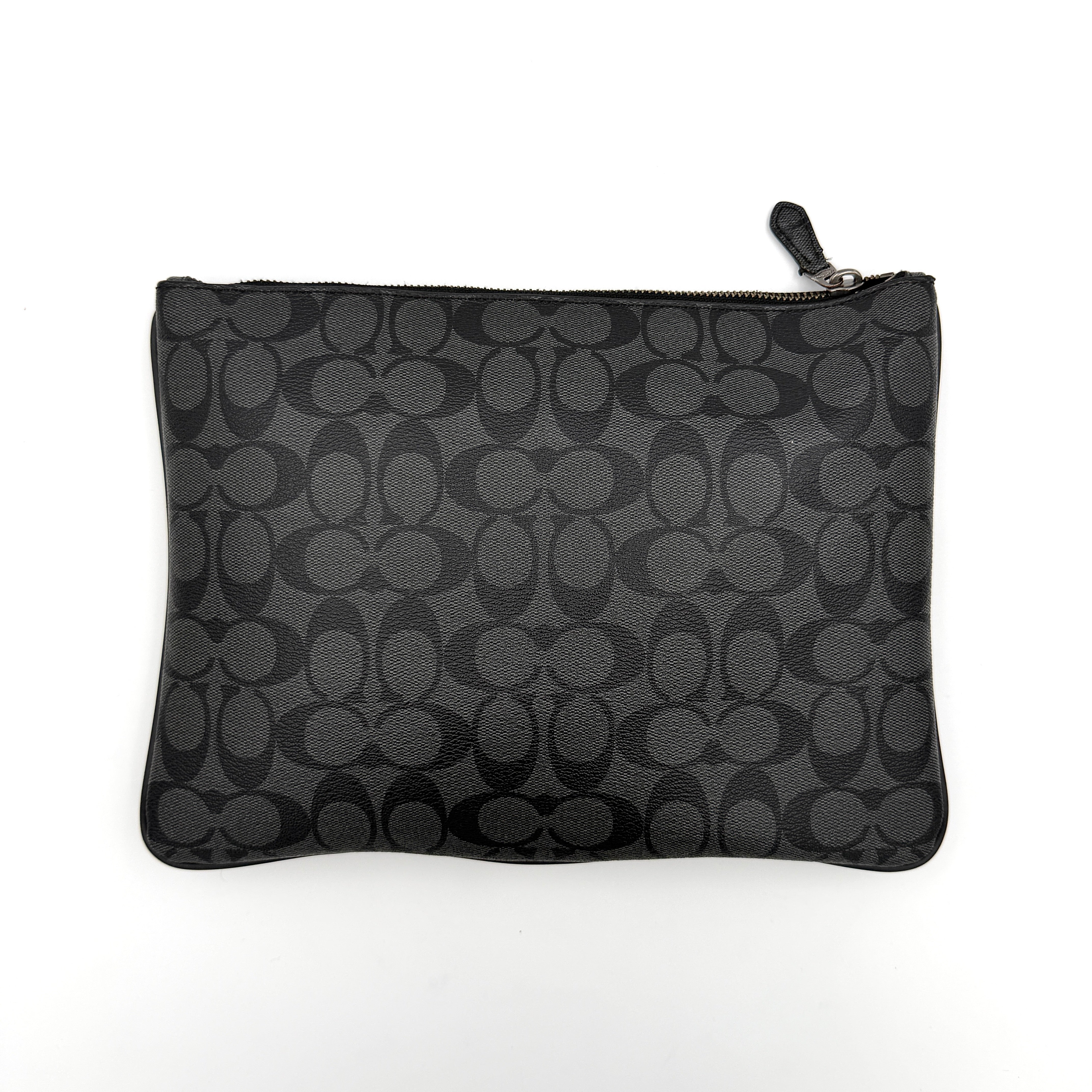 Coach Signature large pouch in black coated canvas with navy and cream varsity stripes, shown from the front with a zip top.