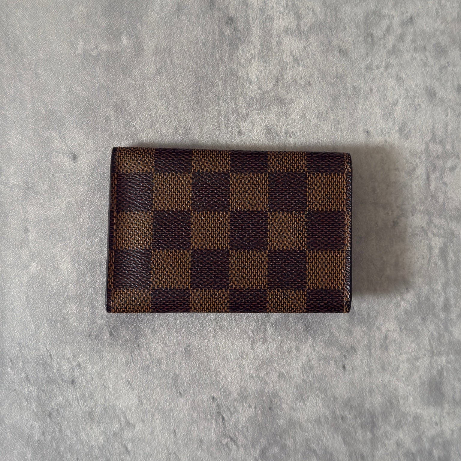 Pre-loved Louis Vuitton Damier Ebene Key Holder with Six Gold-Tone Hooks, Luxury Vintage Designer Accessory with Snap Button Closure.