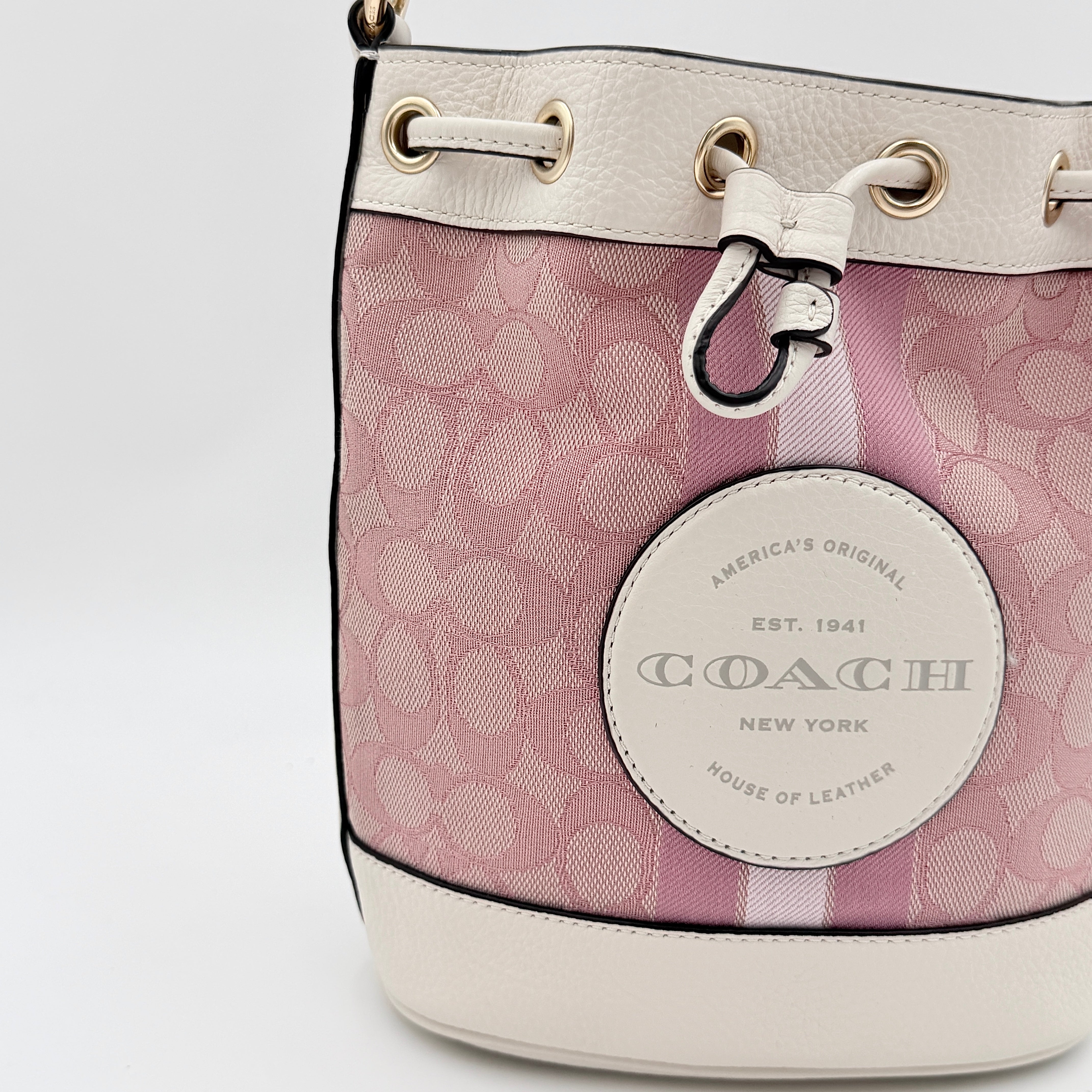 Coach Signature Dempsey 19 bucket bag in pink and white canvas with white leather trim and detachable strap.