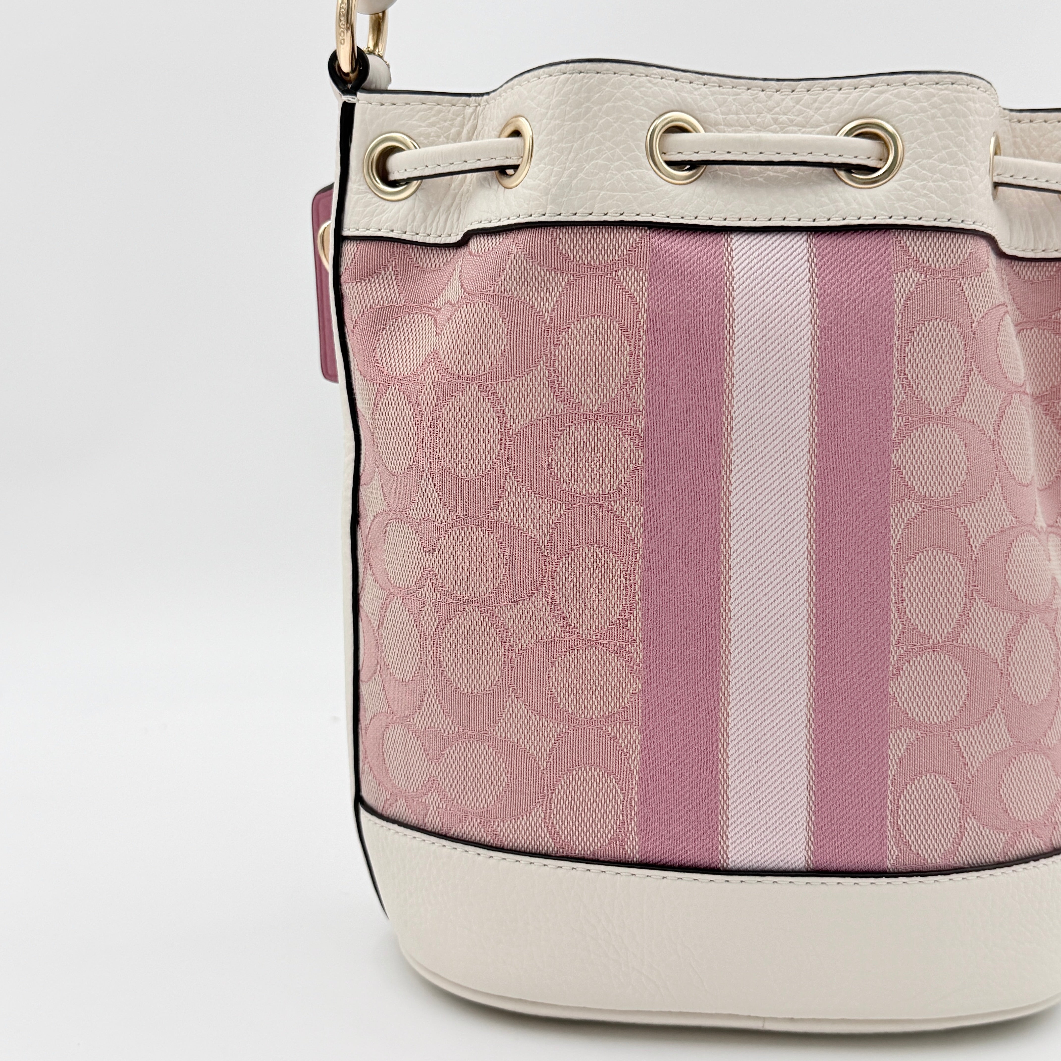 Coach Signature Dempsey 19 bucket bag in pink and white canvas with white leather trim and detachable strap.
