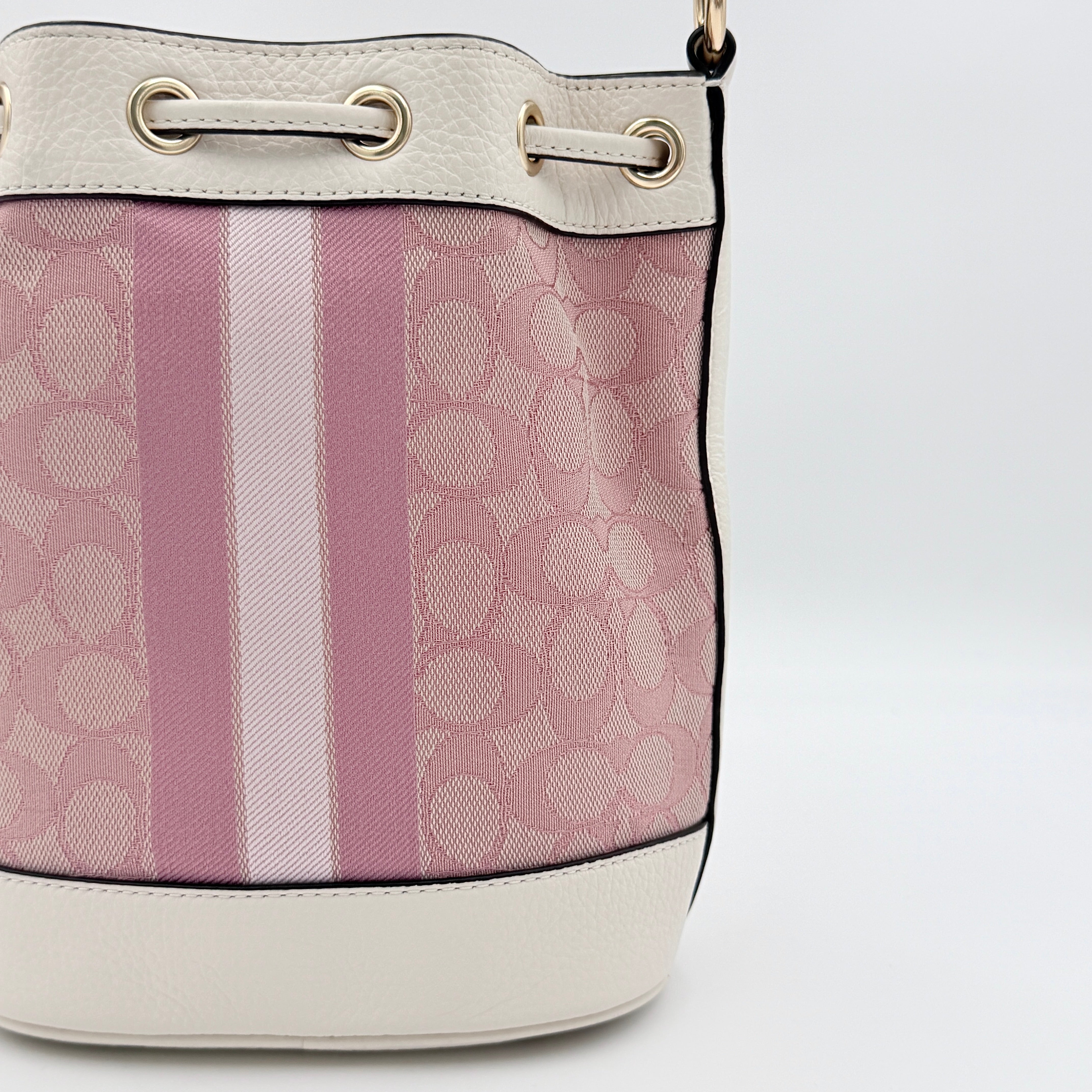 Coach Signature Dempsey 19 bucket bag in pink and white canvas with white leather trim and detachable strap.
