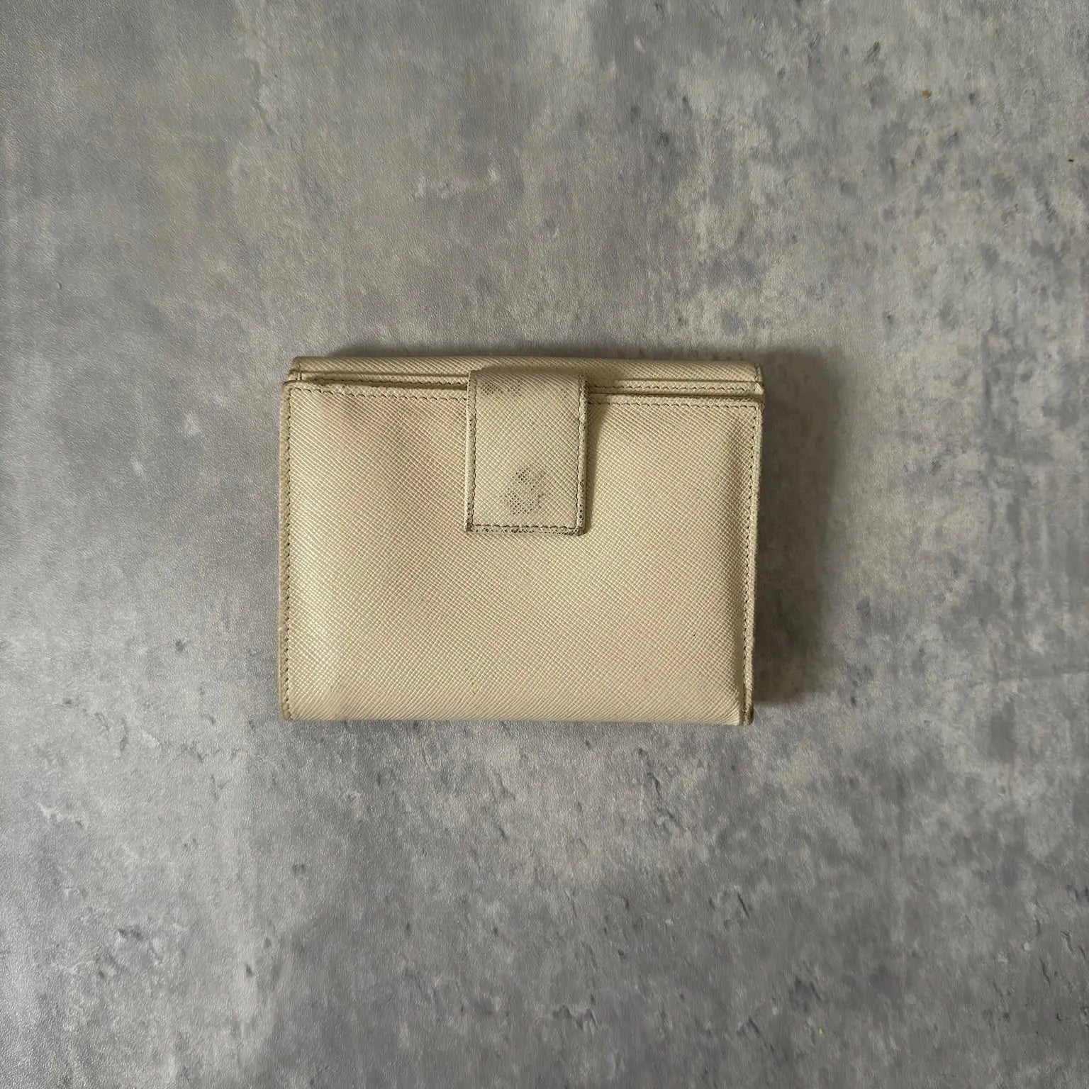 Prada Cream Saffiano Folding Leather Wallet, crafted from textured Saffiano leather with a gold-tone triangular logo and a compact folding design.