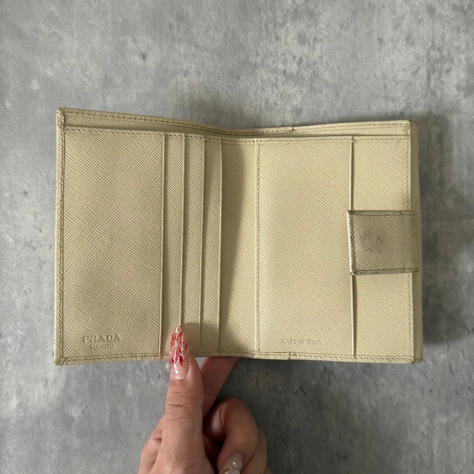 Prada Cream Saffiano Folding Leather Wallet, crafted from textured Saffiano leather with a gold-tone triangular logo and a compact folding design.