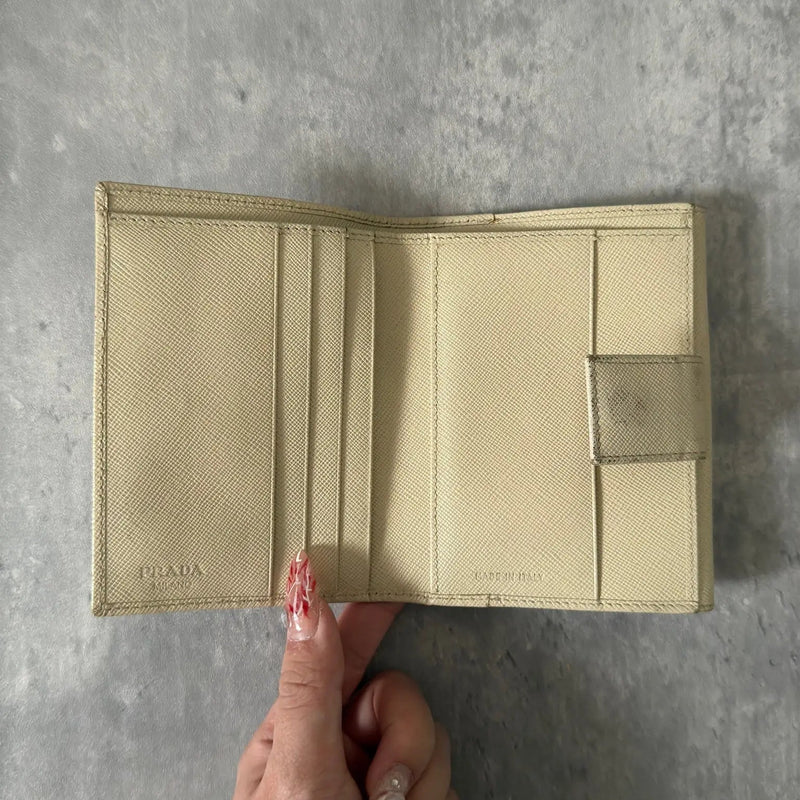 Prada Cream Saffiano Folding Leather Wallet, crafted from textured Saffiano leather with a gold-tone triangular logo and a compact folding design.
