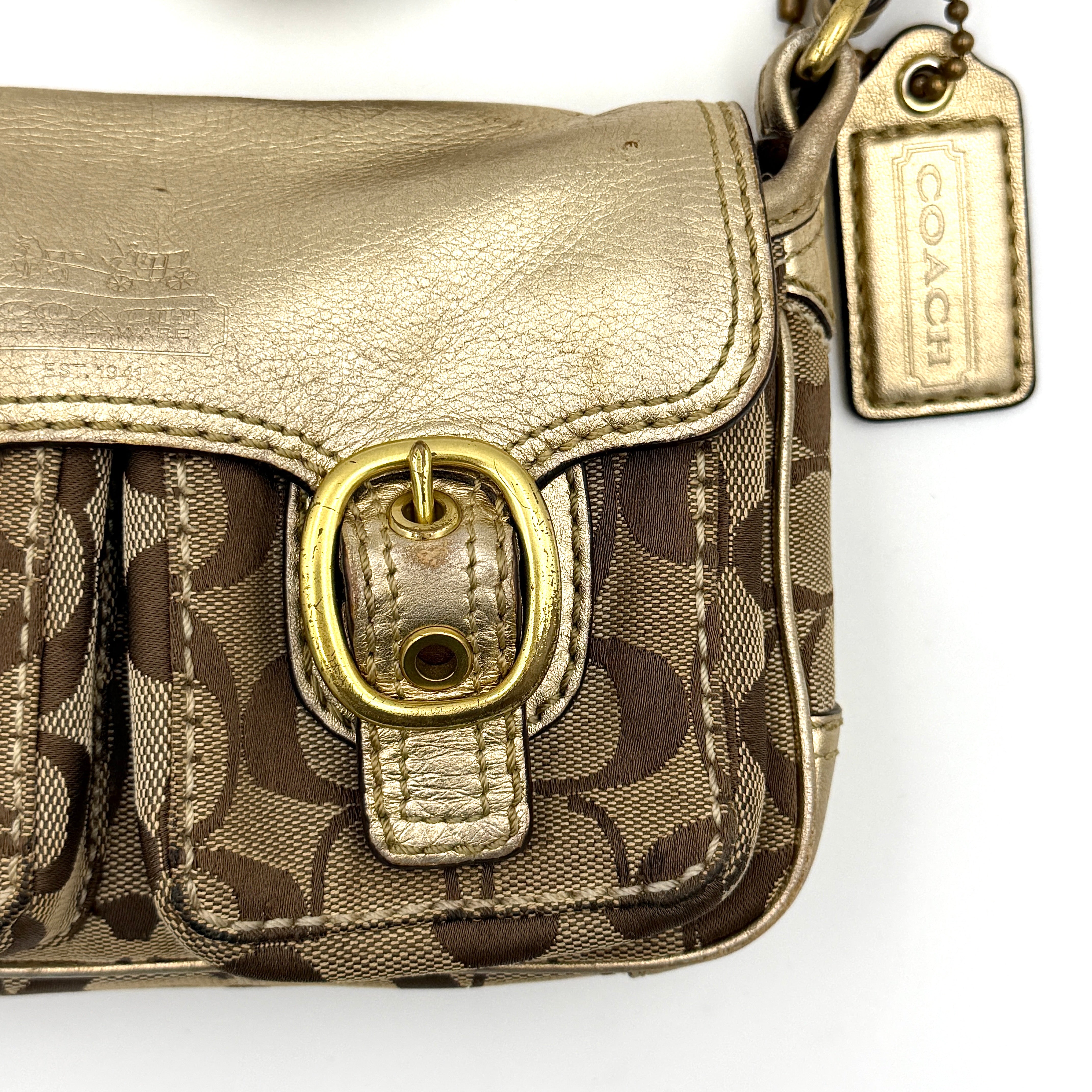 Coach Bleecker crossbody bag in gold metallic leather and beige monogram canvas with double front buckle details.