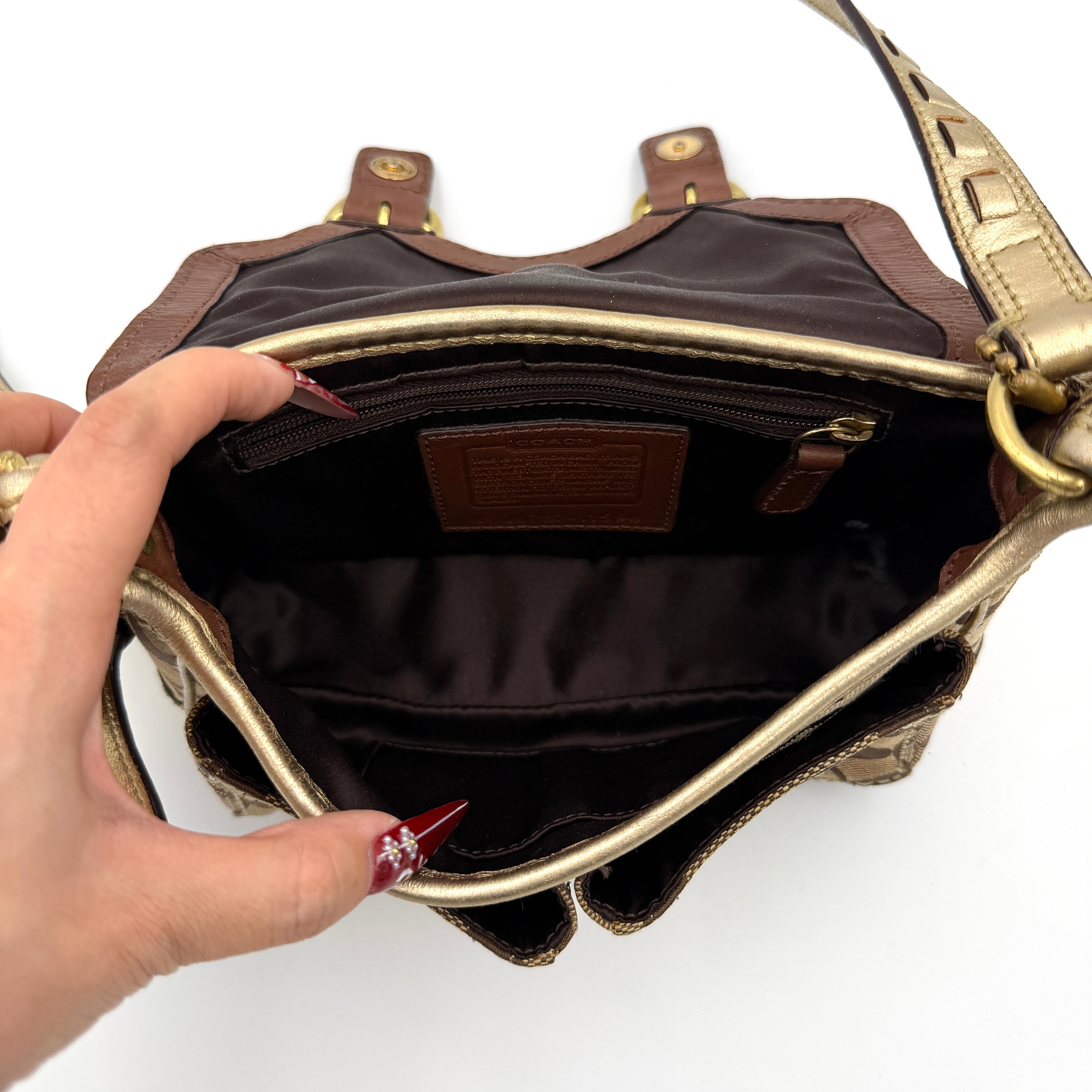 Coach Bleecker crossbody bag in gold metallic leather and beige monogram canvas with double front buckle details.