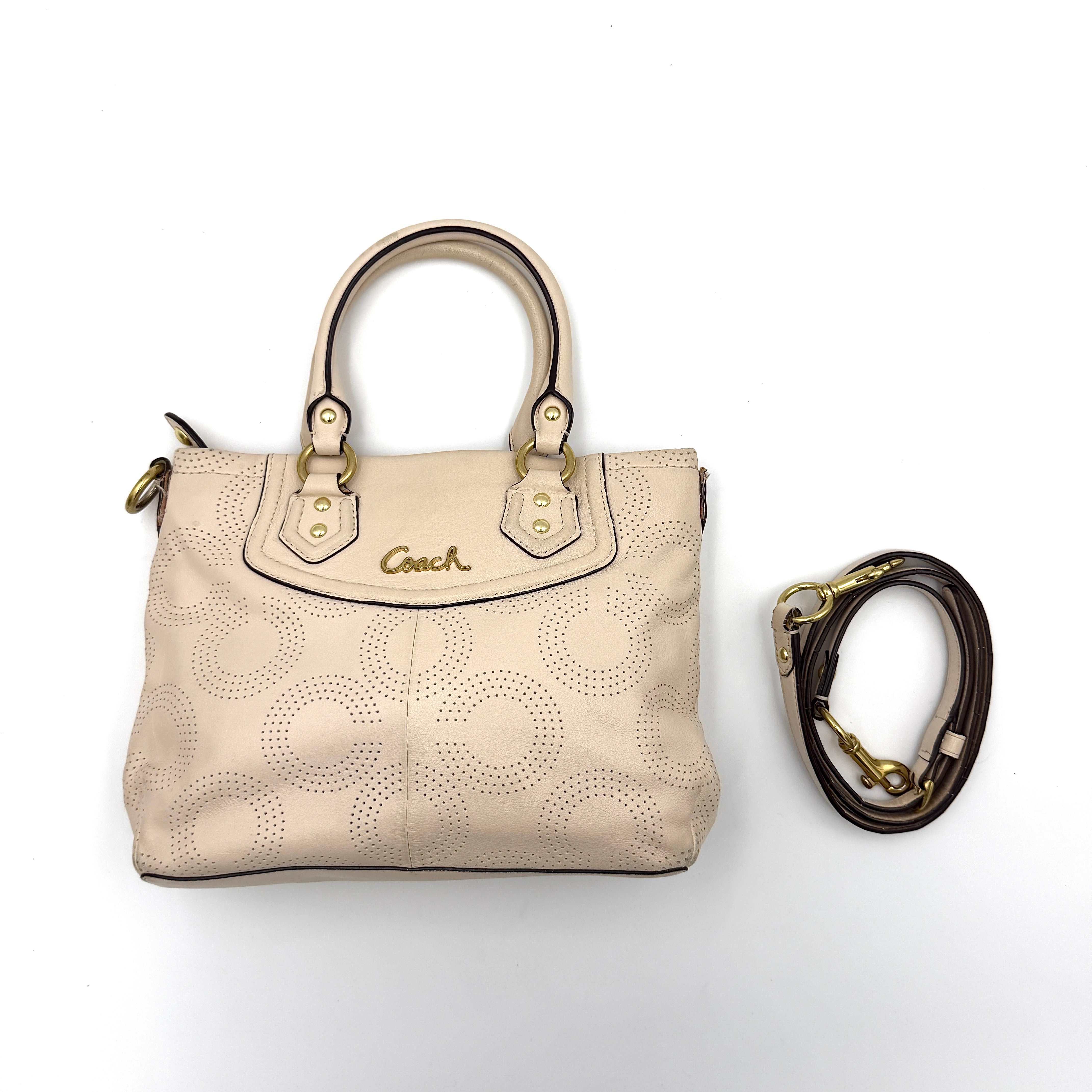Coach Ashley 2Way cream perforated Op Art leather handbag with dual handles and detachable strap, styled on a white background.